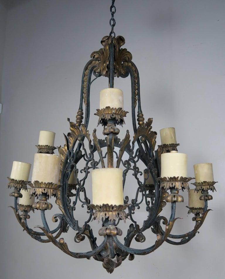 19th century Spanish Baroque style wrought iron twelve-light painted and parcel-gilt chandelier. The fixture has been newly rewired with drip wax candle covers and includes chain and canopy.


Measures: Height 41 in. x diameter 38 in.