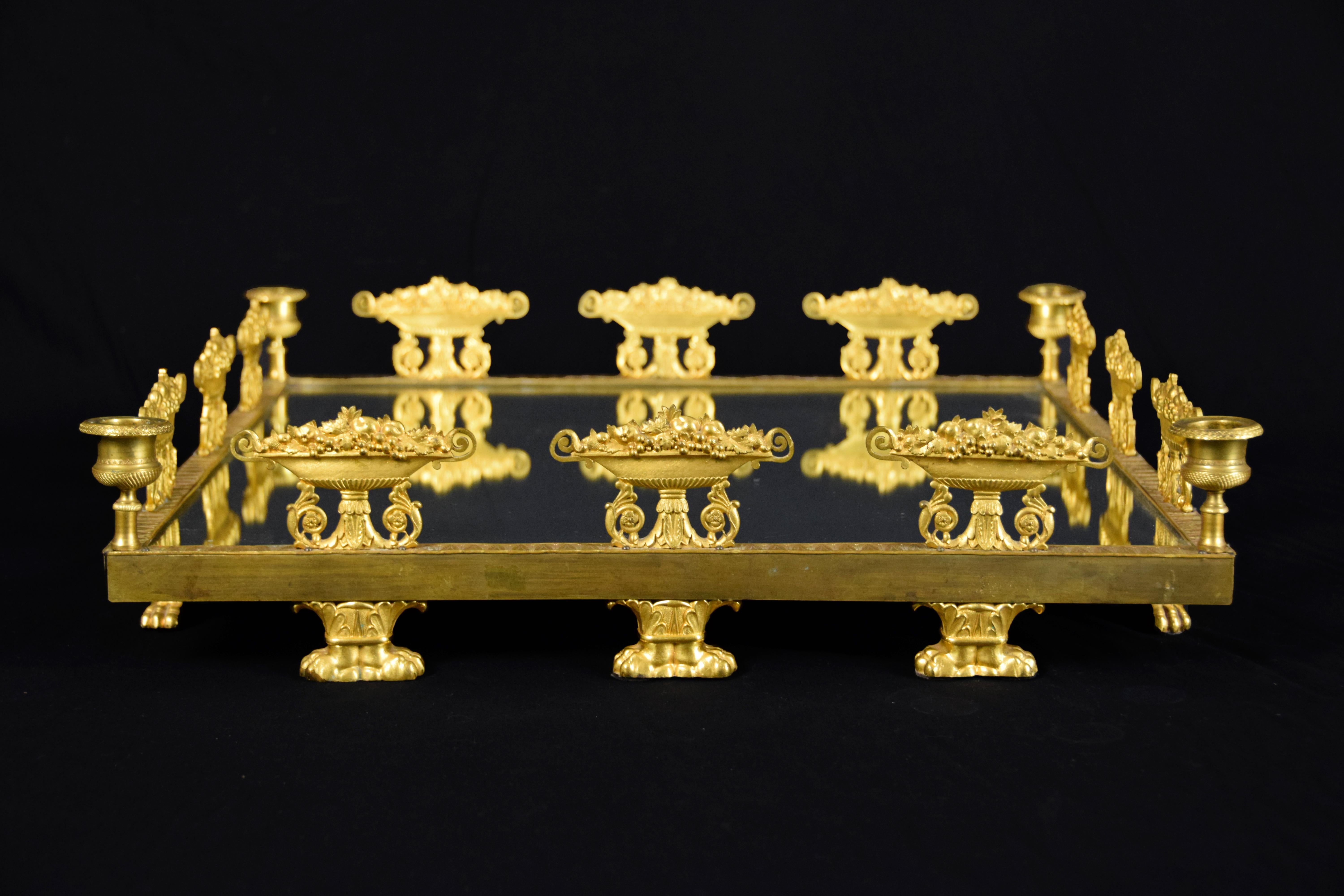 19th century square gilt bronze Empire centerpiece finely chiseled.

This splendid Empire French centerpiece has a square base covered by a mirror, surrounded by a frame made of finely ormolu bronze. The perforated frame is decorated with vases