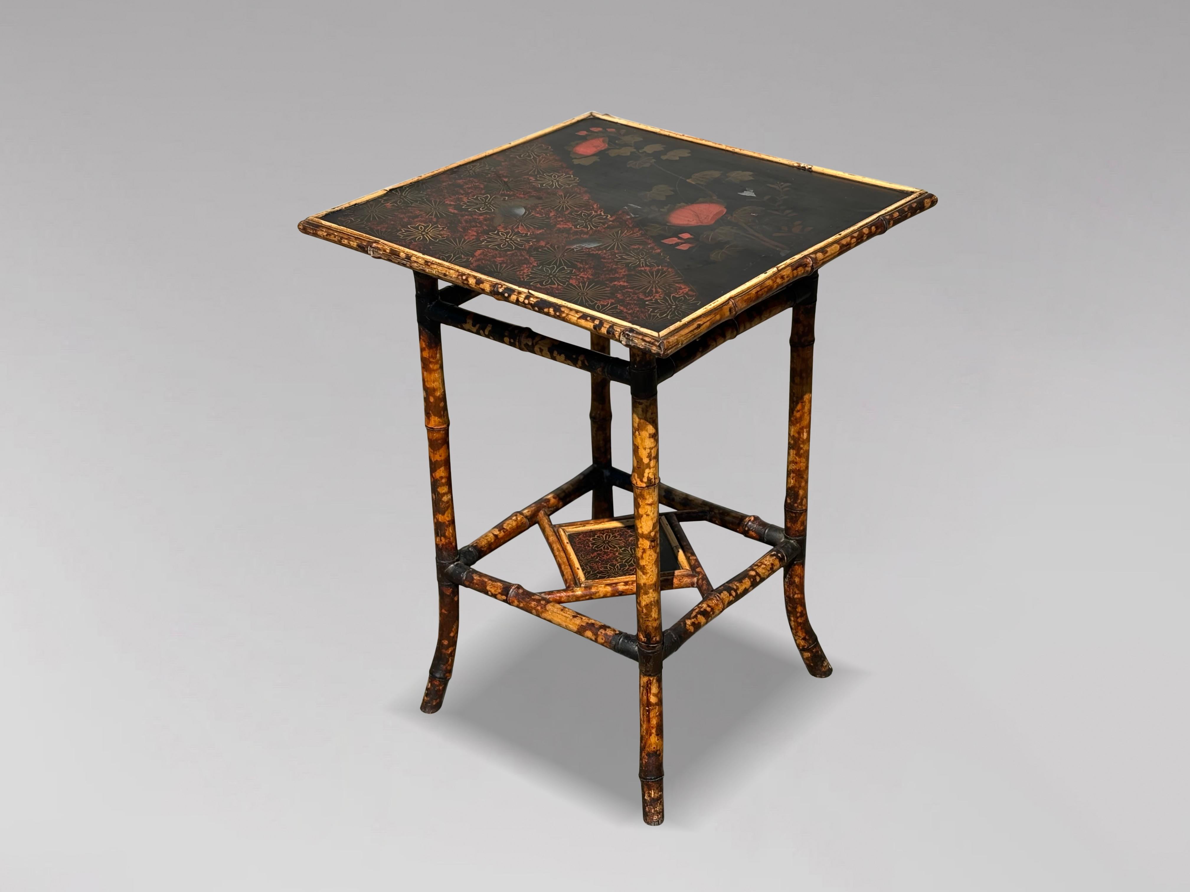 A late 19th-century Victorian period two-tier tiger bamboo side table with the original hand-painted top. This pedestal side table features a hand-painted scenic top portraying a bird with floral scenery. The square table has an attractive design, a