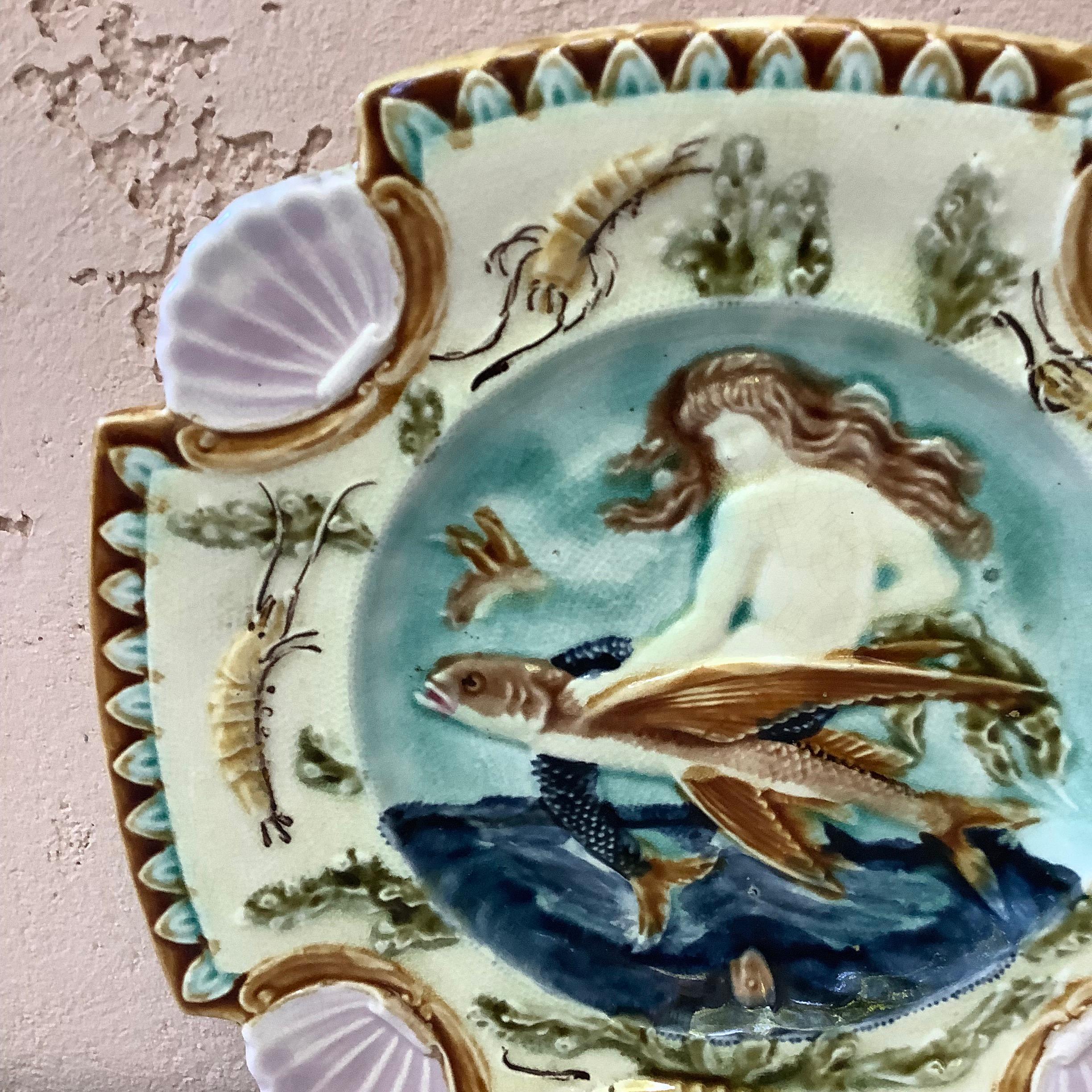 Square Majolica mermaid plate with shells on the corners, the mermaid sit on a flying fish, the border is decorated with shrimps, circa 1880.