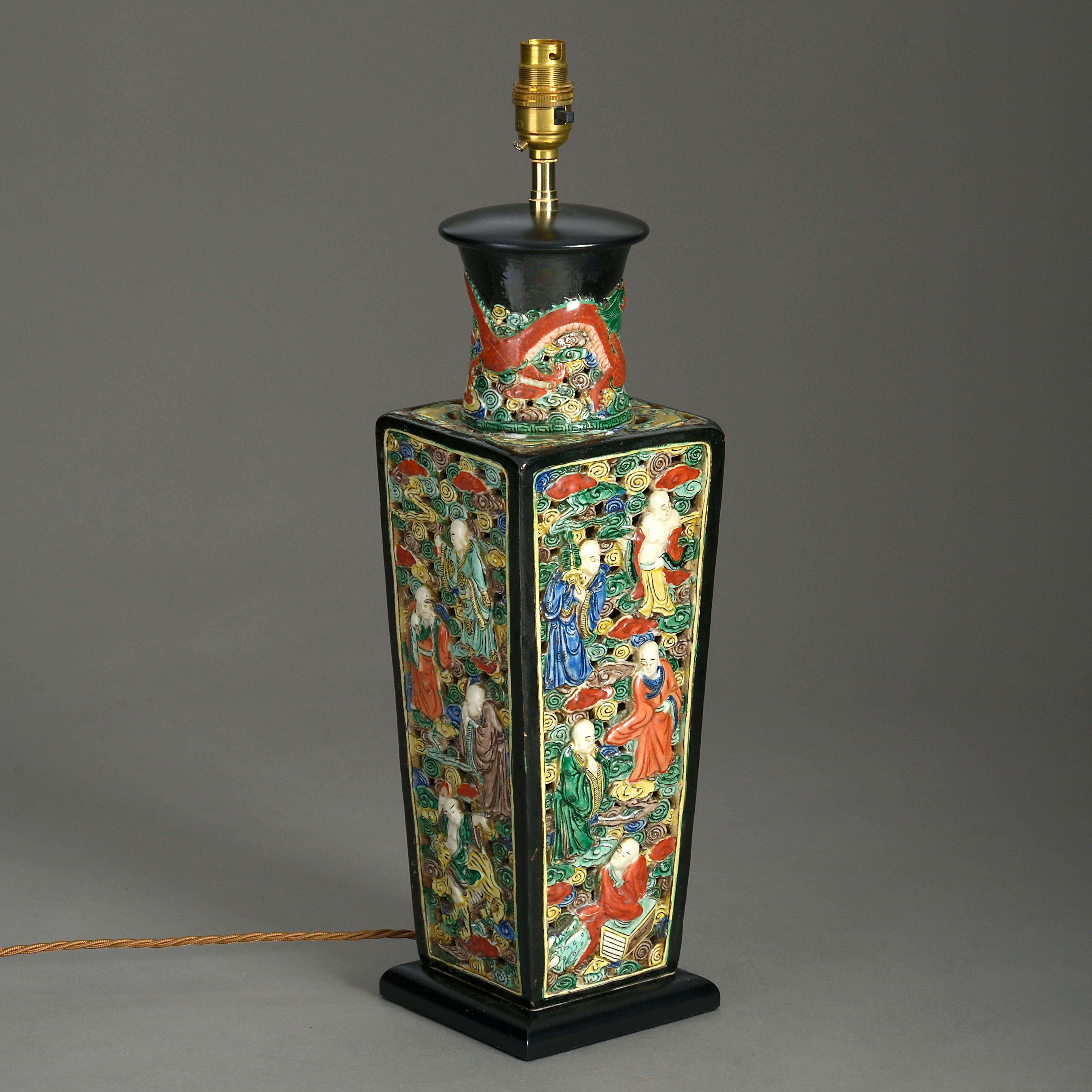 A mid-19th century polychrome vase of square tapering form, the black glazed neck with dragon motifs, the sides intricately worked with figurative scenes upon a pierced scrolling ground. Now mounted as a table lamp.

Wired for electric lighting