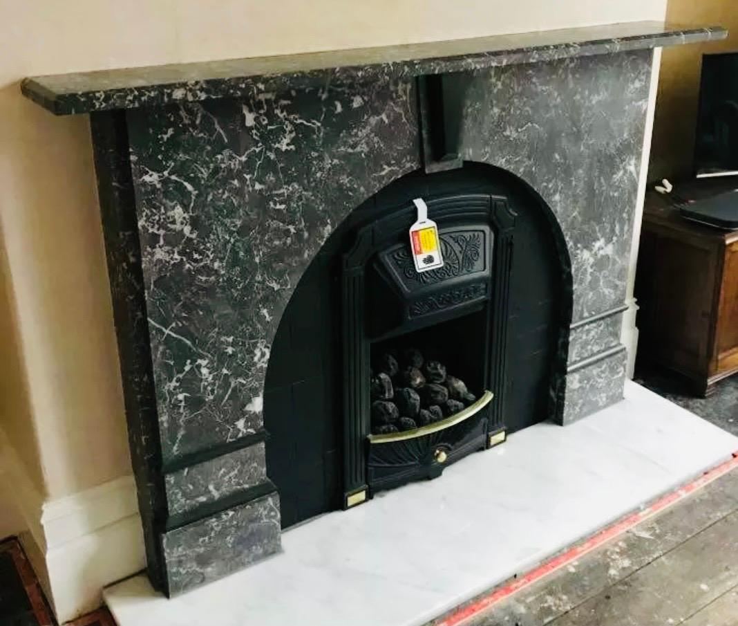 A simple and striking late 19th century St Annes marble fireplace surround, a beveled top shelf rests above a central tapered keystone with a raised tablet of Belgian black marble, flanked by handed arch spandrels with intermittent Belgian black