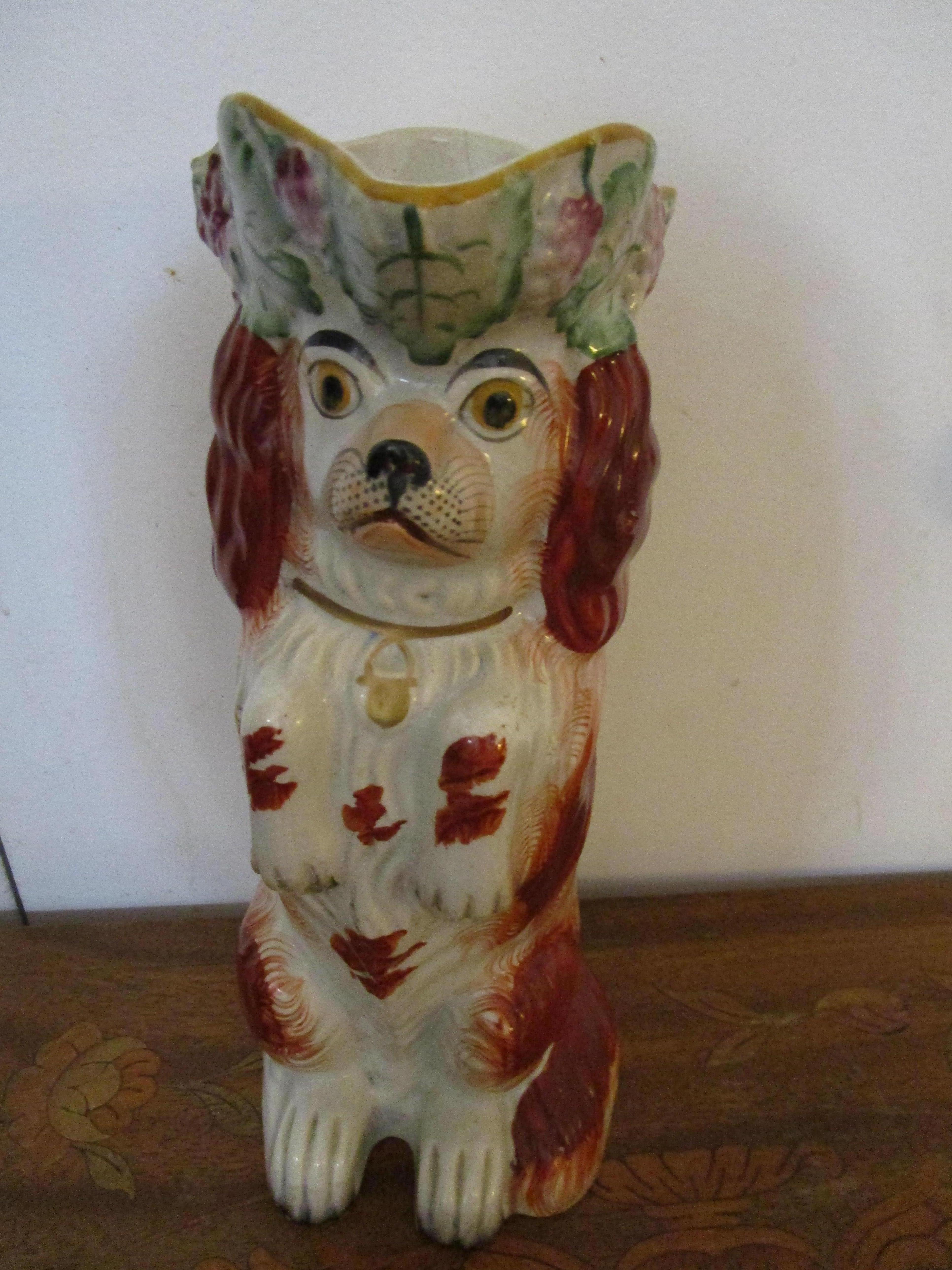 This Staffordshire Spaniel jug is impertinent, from his expression to his hopeful gaze. The eyes seem animated and almost lifelike. This jug is in excellent condition with bright red, white and green and gilt touches in the form of the pup's gold