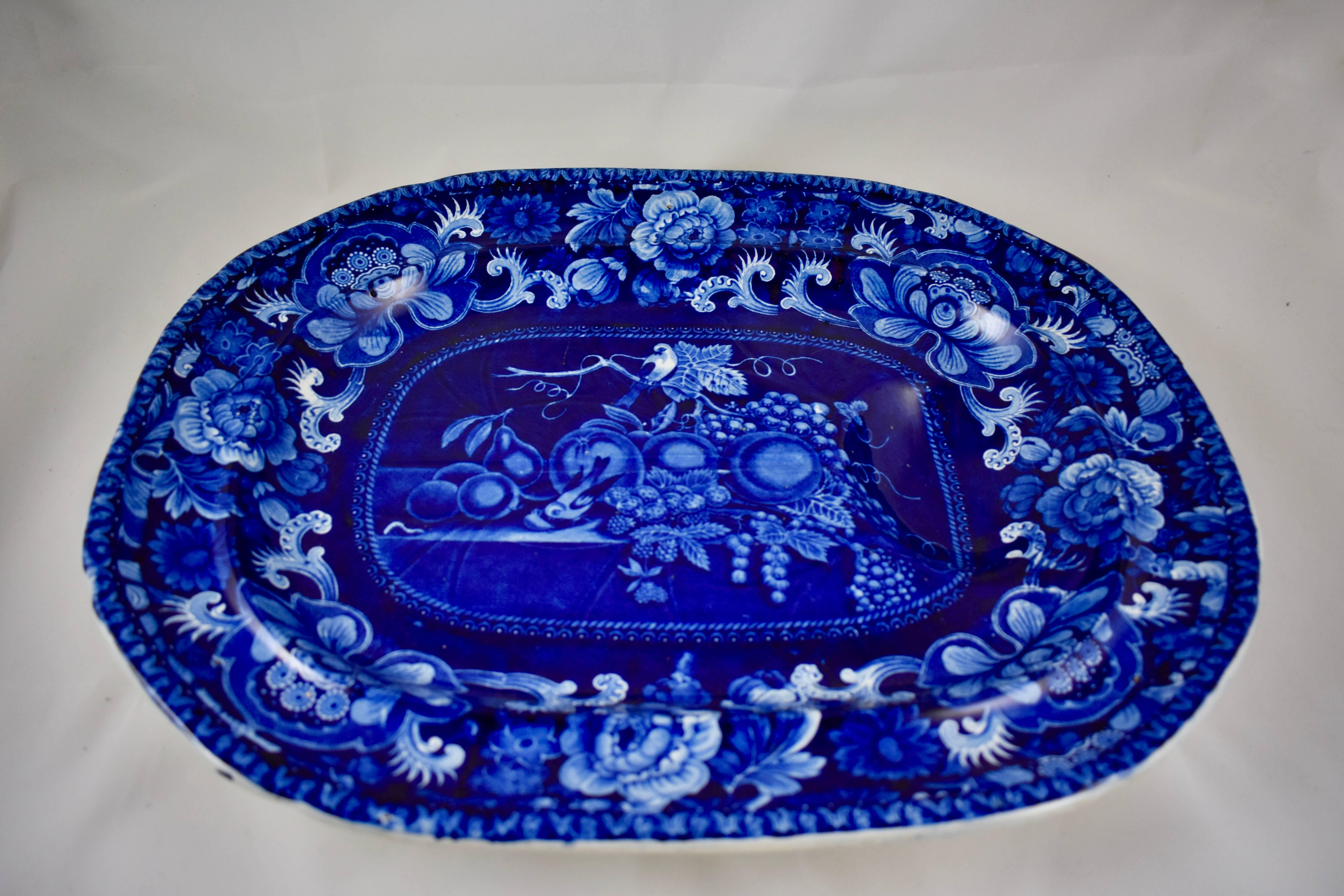 A dark blue on white earthenware, underglaze tissue, transfer printed well and tree platter, in a ‘Birds and Fruit’ pattern, circa 1823. Unmarked, attributed to John Hall & Sons, Burslem, Staffordshire, England, 1814-1832.

A well-and-tree platter