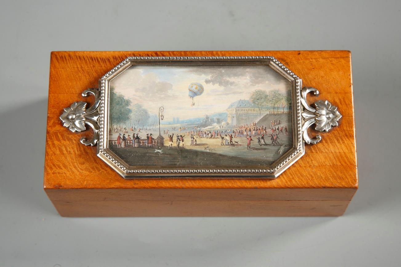  Casket in light wood box with a miniature on its lid. This gouache presents the flight of the a hot air balloon 