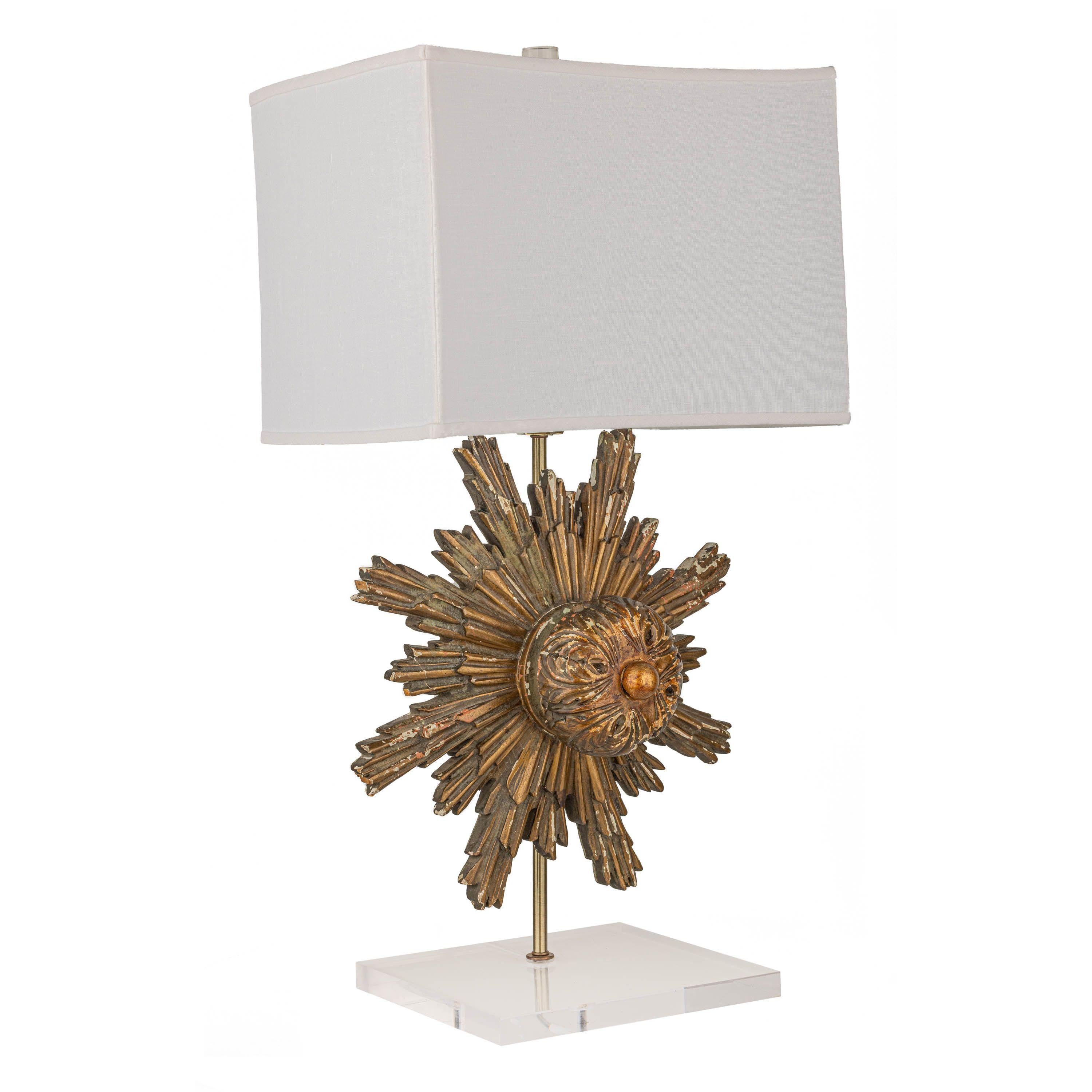 Carved three-dimensional gilt starburst attached to a metal rod and mounted on an acrylic base. Acrylic cylinder finial and white linen shade, which has a convex shape on the wide sides making this lamp truly special.
Starburst measures roughly 18