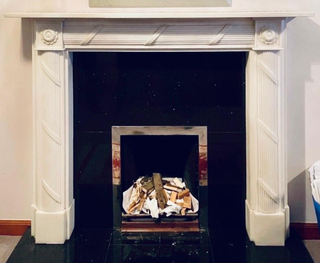 A medium sized 19th century Regency style hand carved statuary marble fireplace surround, a reeded top shelf sits directly above a stepped frieze with carved ribbon and reeding, flanked by framed high relief circular pateraes to the end blocks,