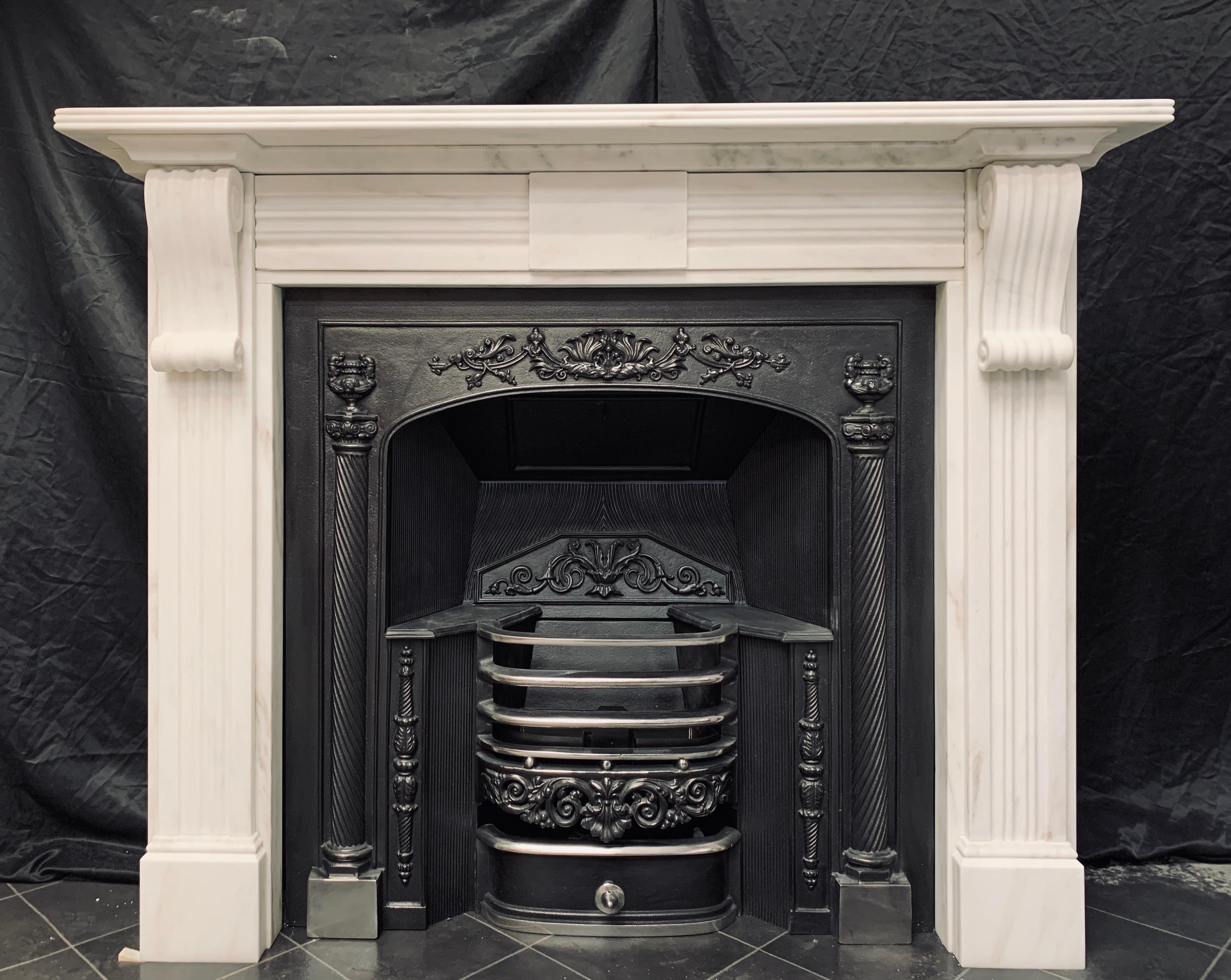 A medium and very clean 19th century lightly veined statuary marble Regency style fireplace surround. A generous reeded shelf and secondary corveto cornice rests above a frieze hosting a central unadorned tablet flanked by deep moulded side panels,