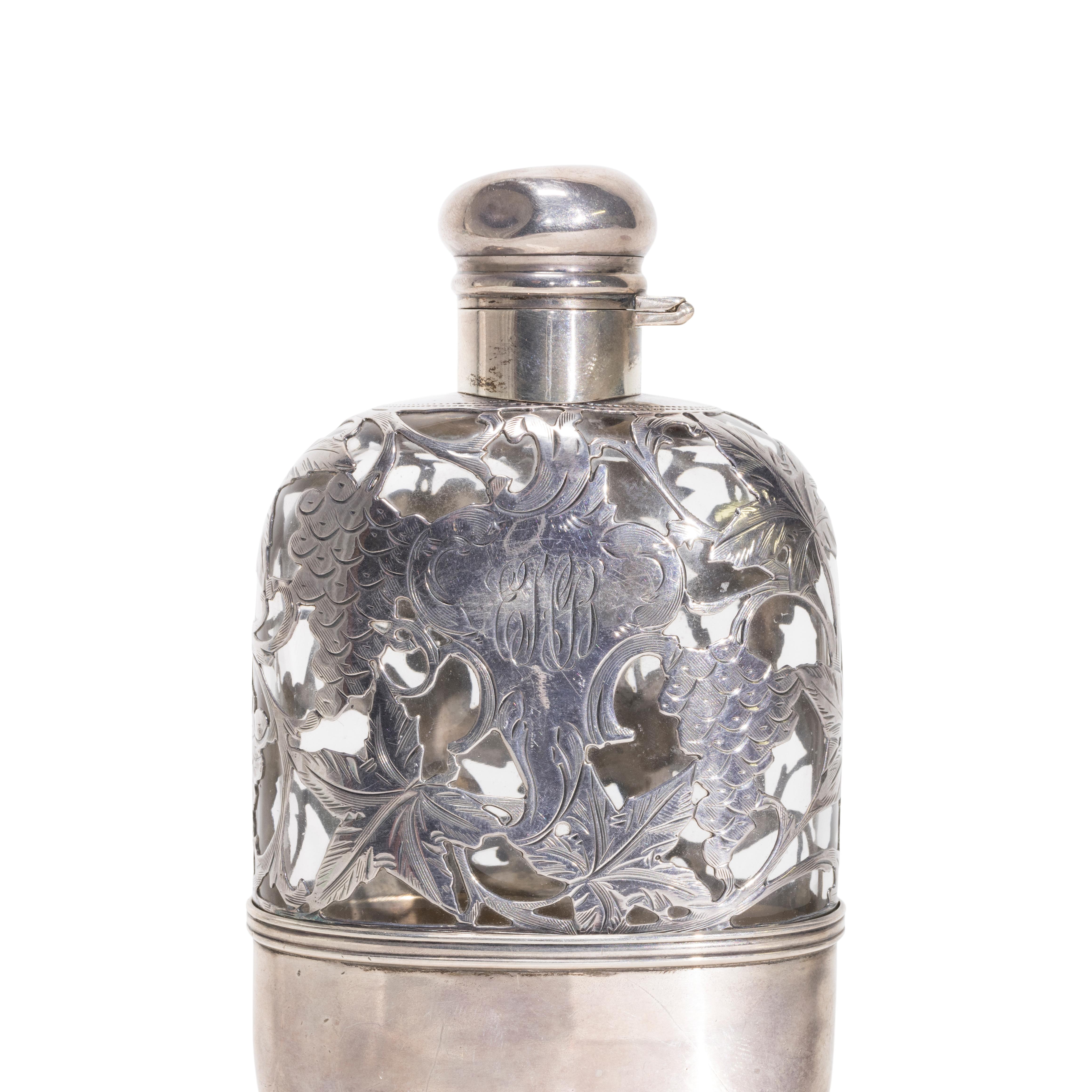 Fiaschetta in vetro rivestita in argento con motivo di uva e vite. Il fondo è marcato Sterling, 1 Pint, Serial #4123 e marchio del produttore. Coperchio a vite con cerniera.

PERIODO: XIX secolo

ORIGINE: Inghilterra, Europa

DIMENSIONE: 6