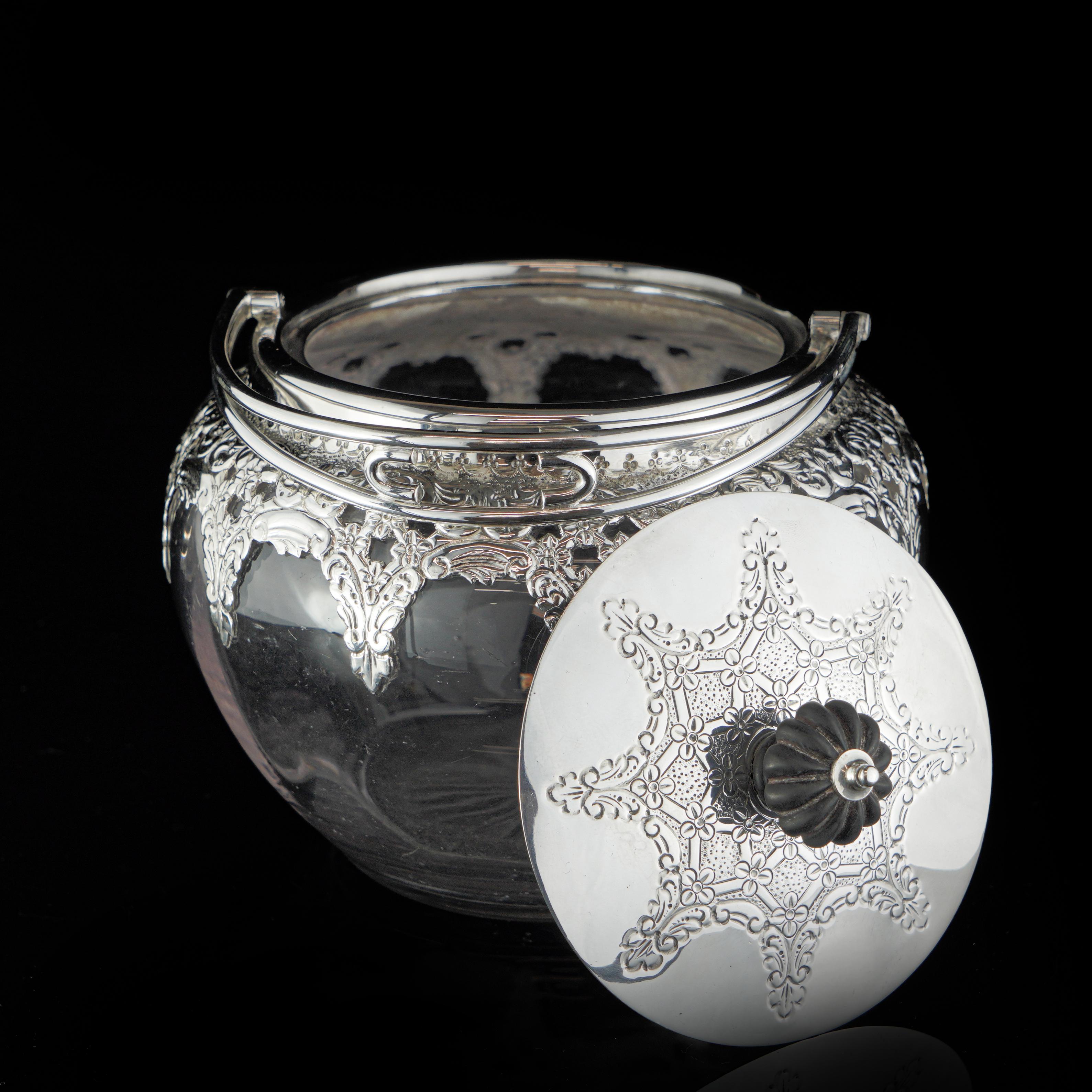 Antique 19th Century sterling silver and glass cookie jar/caddy with swing handle.
 Maker: Thomas Latham & Ernest Morton
 Made in England, Birmingham, 1896
 Fully hallmarked.

 Approx. Dimensions - 
 Diameter x height: 14 x 14 cm 
 Weight: