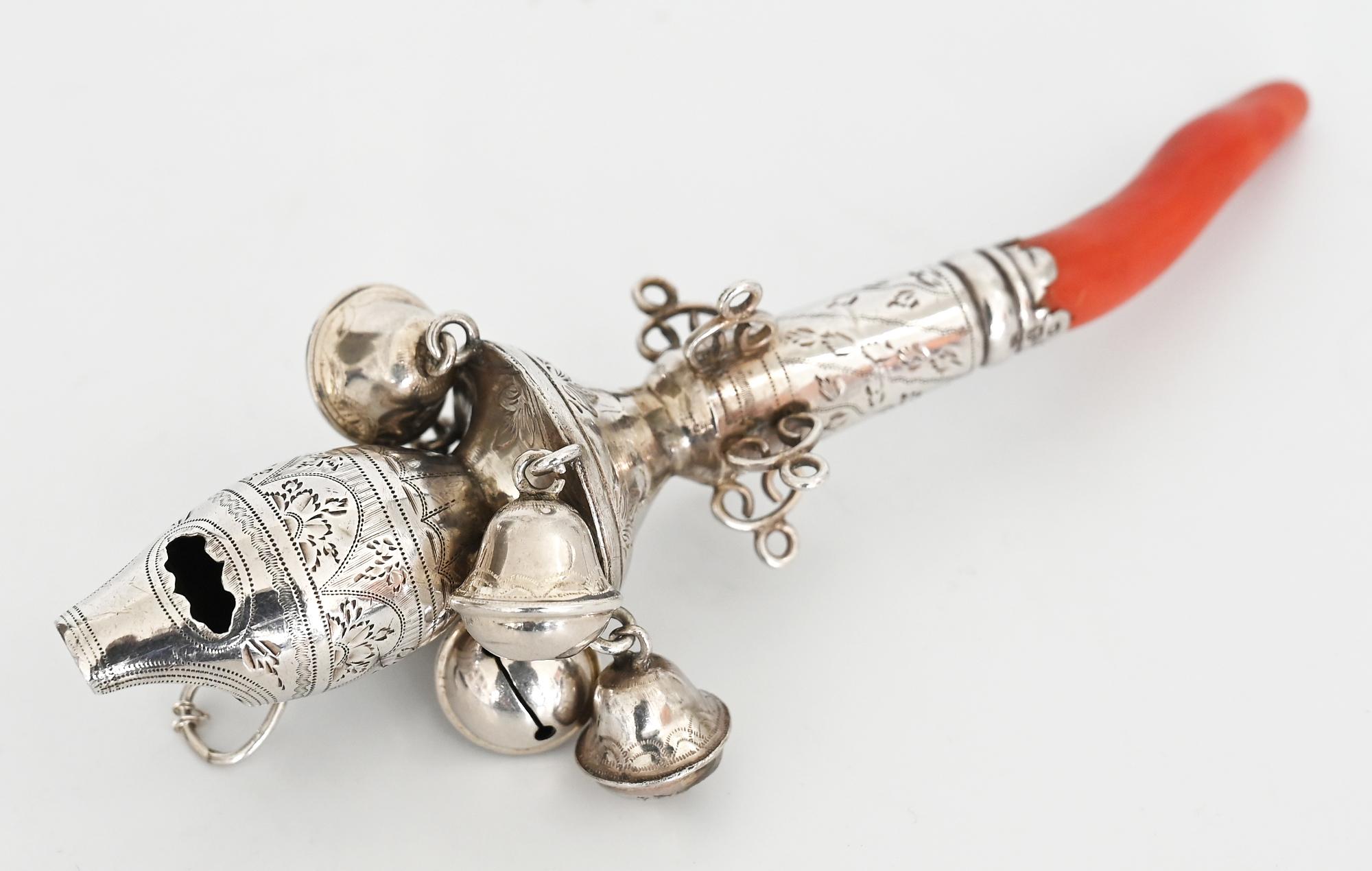 Very beautiful baby rattle, with an pipe, made out of sterling silver baby and coral.
It was made in Birmingham 1852 in a very fine elaboratition, which you can see especially in the encraving.
Besides the five glocks, there is also an
Mm: EN.
  