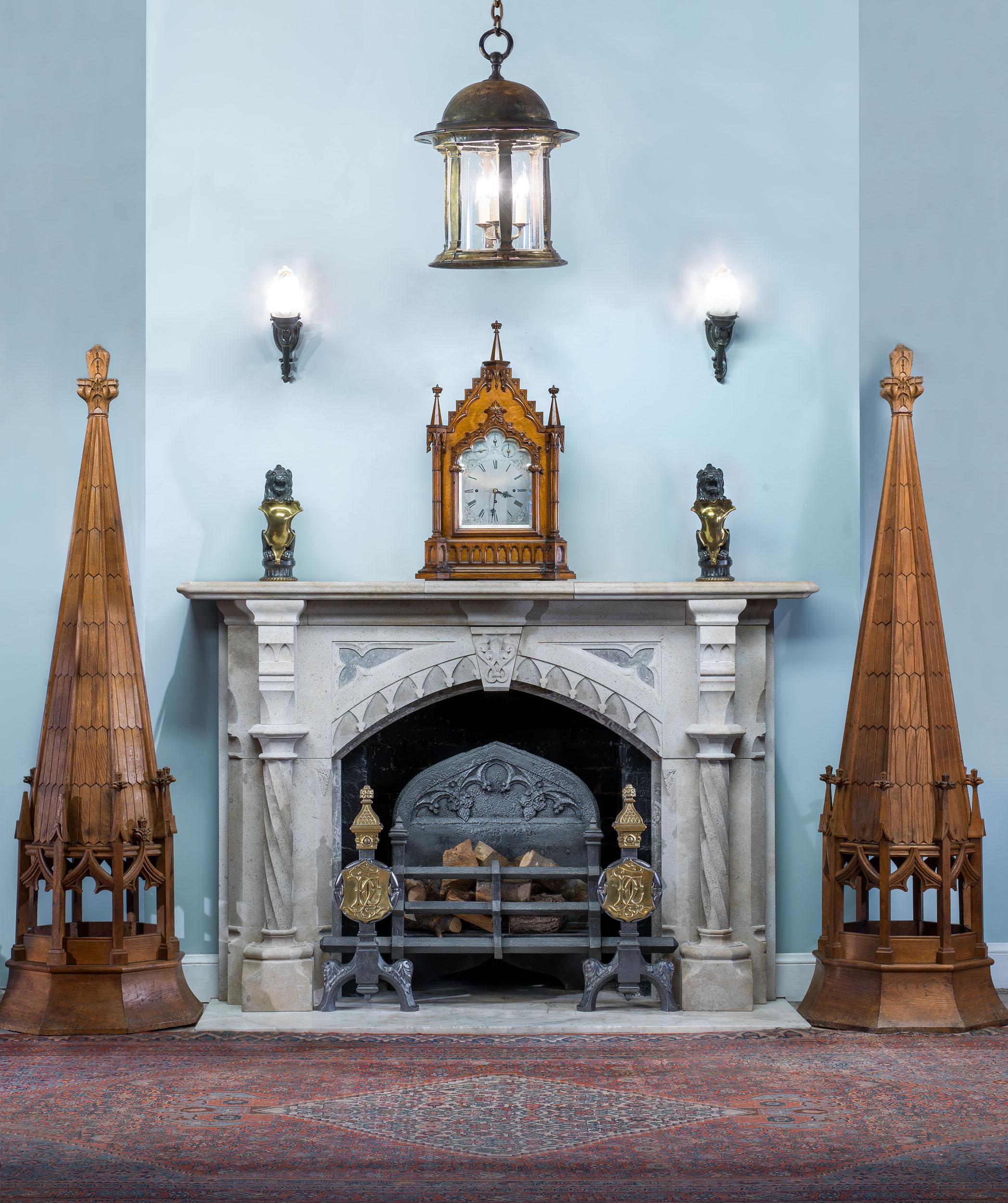 An antique Gothic Revival Hopton Wood stone fireplace of grand proportions. The wide shelf is supported by a carved fleur de lys keystone, which is flanked by trefoil spandrels over a Tudor arch. Twisting pilasters are mounted in front of wide, flat