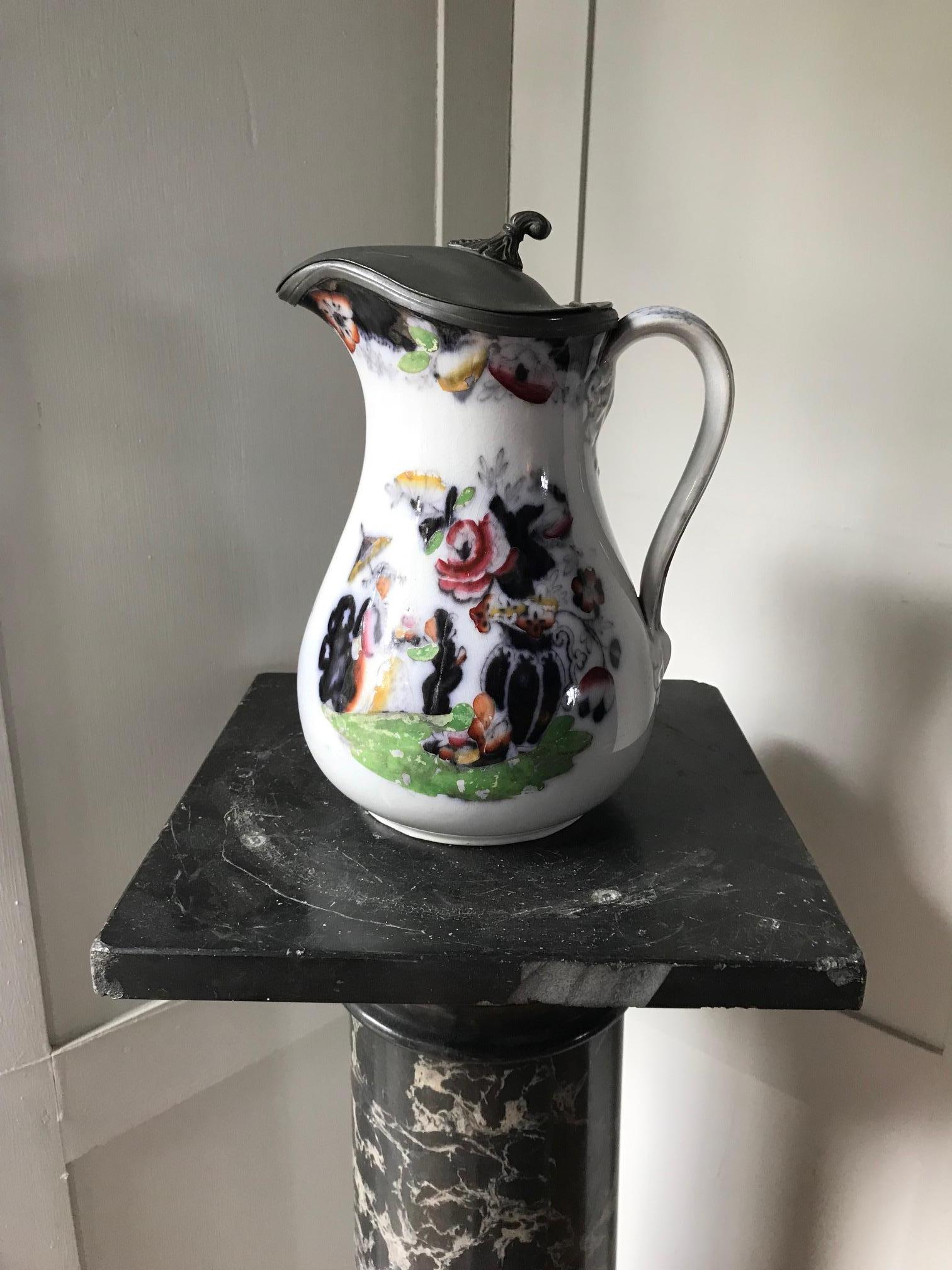 A pretty white pitcher decorated with Chinese figures and a hinged pewter lid. Stamped with makers mark T Booth Hanley.