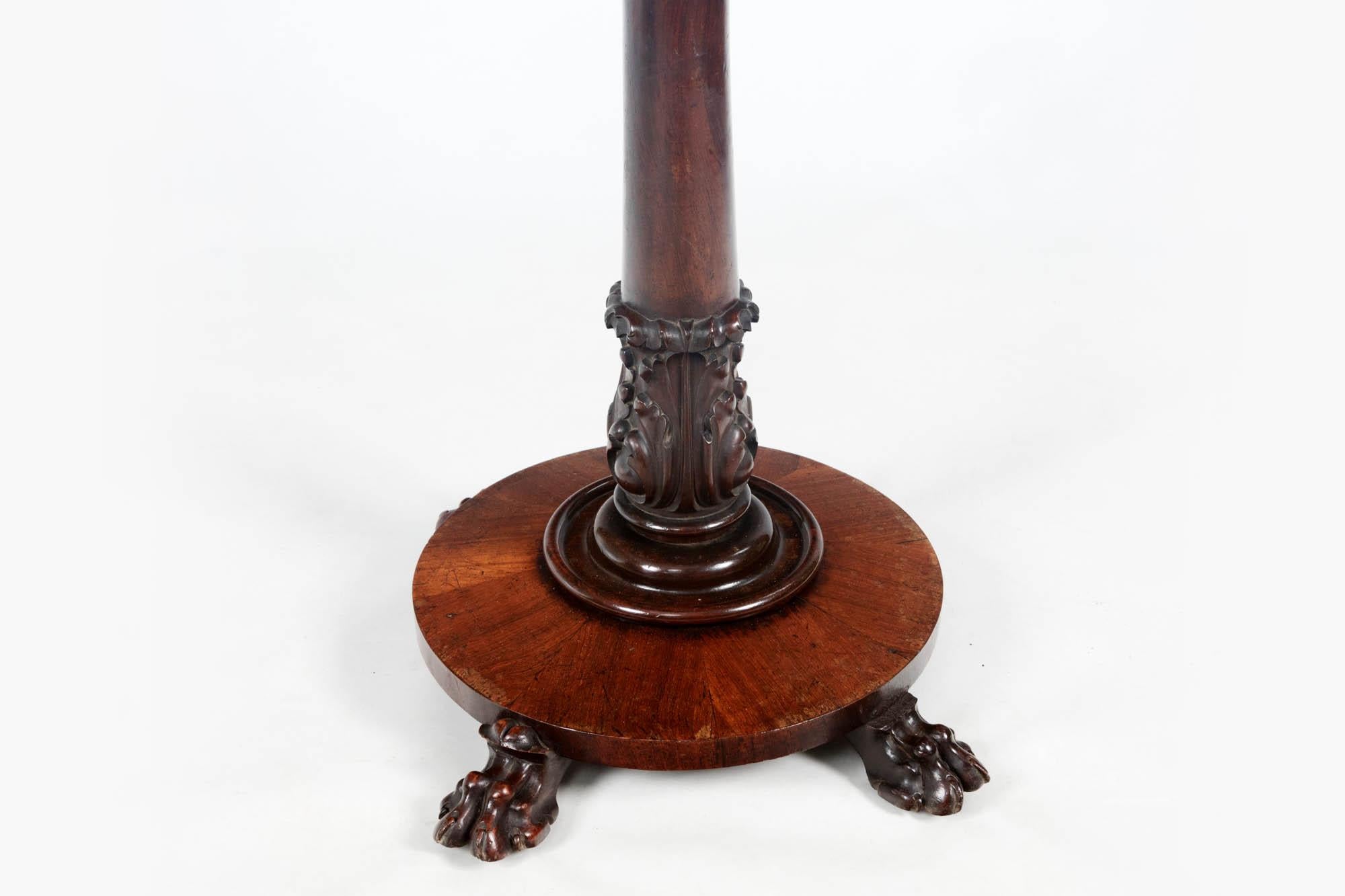19th century occasional table with a rectangular top inlaid with stone specimens forming a decorative chevron pattern. It sits above an elegantly carved mahogany round pedestal pillar base with acanthus leaf decoration and four lion paw feet. Circa