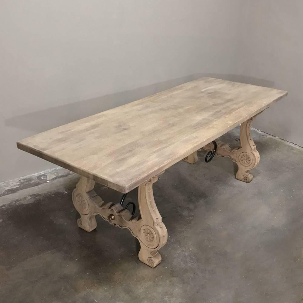Handcrafted from thick, solid planks of old-growth quarter-sawn oak, this handsome 19th century Stripped Oak Spanish dining table features a solid plank top, and hand-forged iron stretchers that have been gracefully scrolled (and accented with a