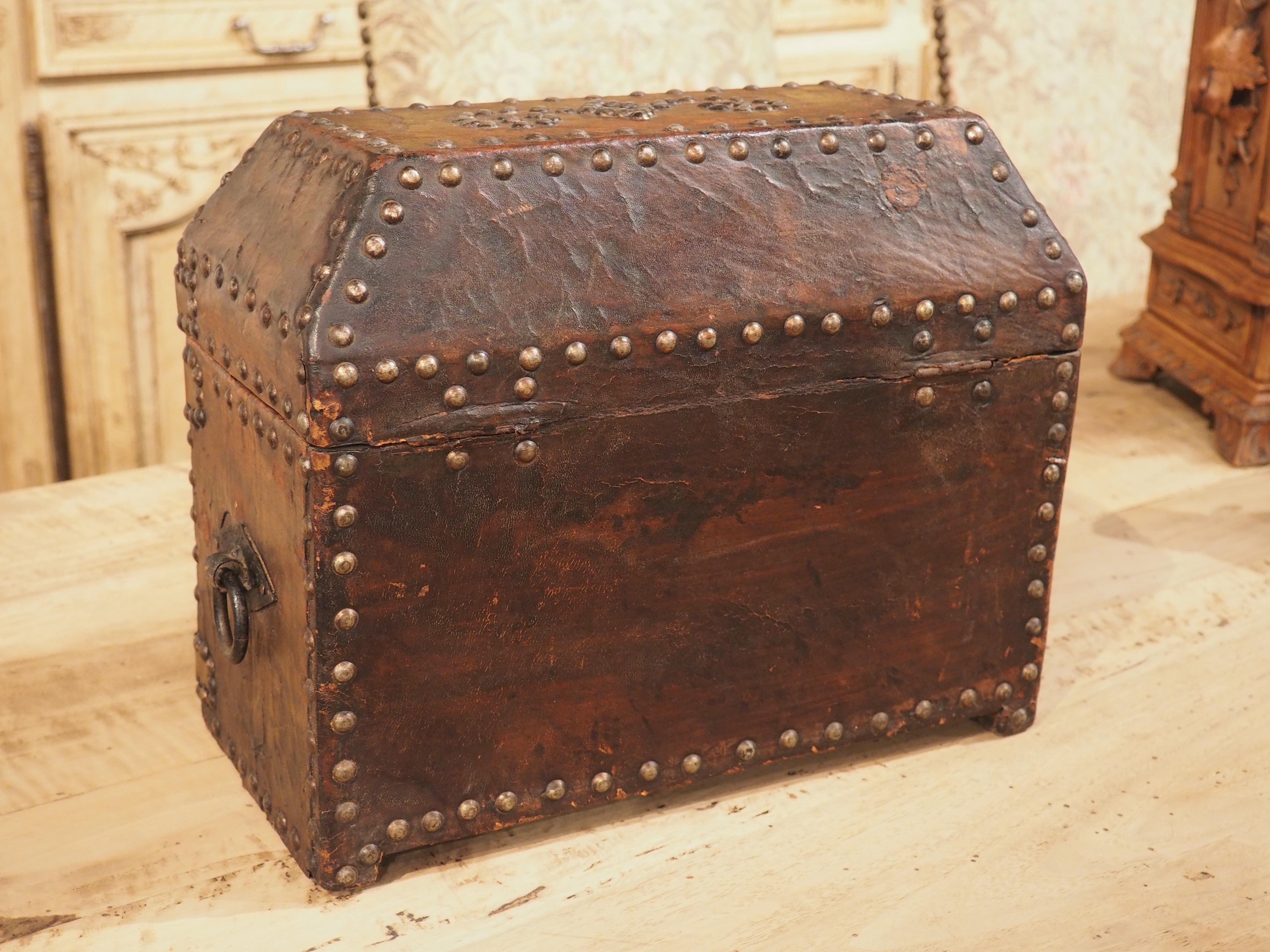 Handcrafted in France during the 1800s, this studded leather table box seamlessly combines functionality and aesthetics. The small rectangular box boasts rich chocolate-colored leather adorned by numerous nailheads, serving both a structural purpose