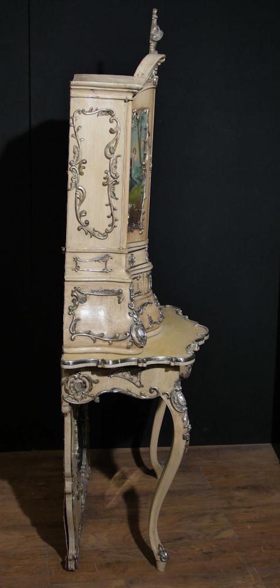 A stunning Italian Florentine cabinet dating to the 1860. Elaborately hand-painted, the decorative panels each have a different romantic scene telling a story.
Profusely adorned with silver plated ormolu mounts with a framed mirror at the base of