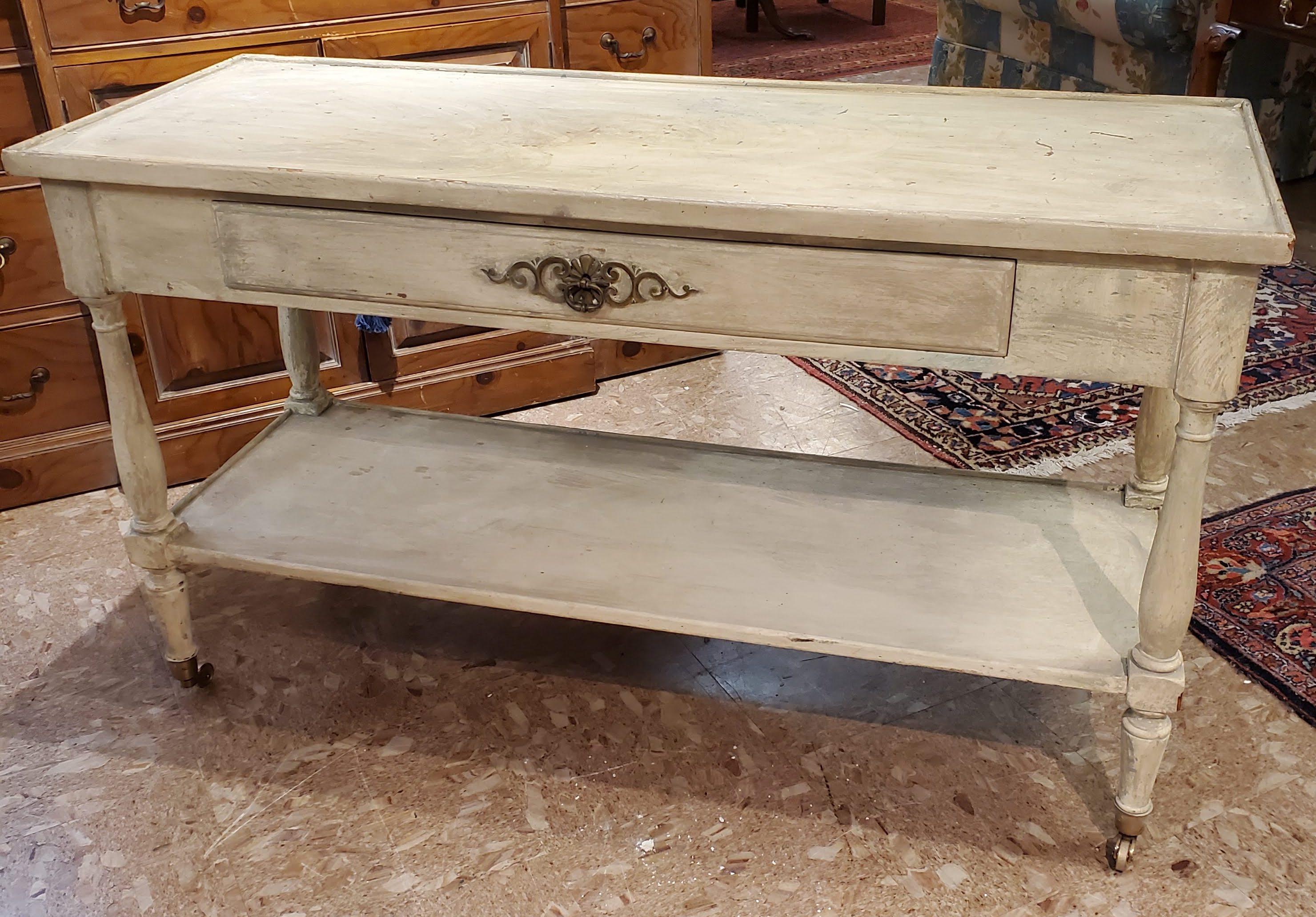 Rustic painted French Provincial style serving table on Caster wheels. Old painted finish made in 19th century style with double sided with false drawer to the rear. Turned legs on brass casters with lower shelf.
France, late 20th