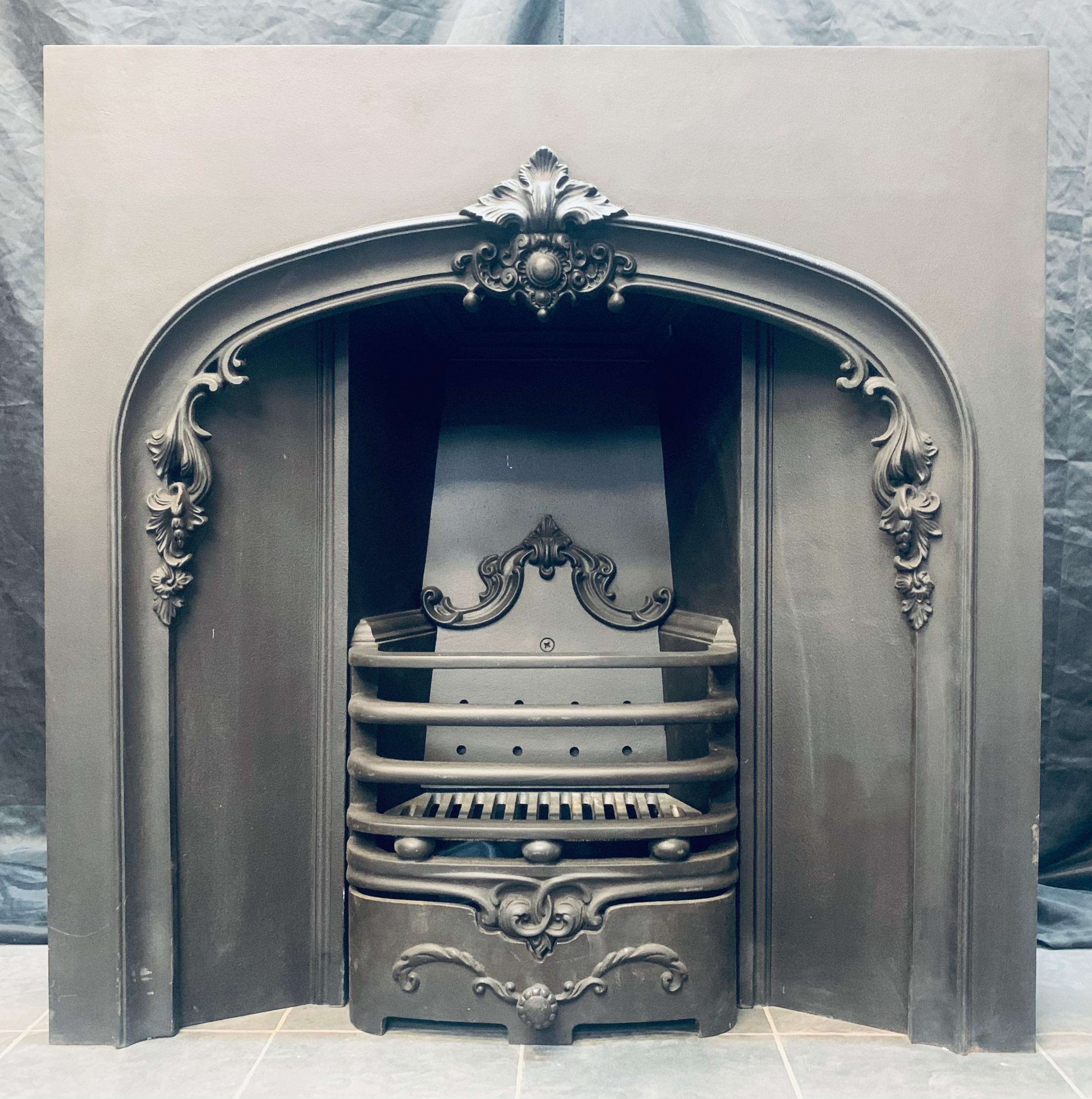 A versatile 19th century Victorian style slow arched cast iron fireplace insert. A slow arched opening with a central cartouche , ingrounds splay inwards to a three barred fire front with cushion spacers, and ash pan cover. Fully complete with