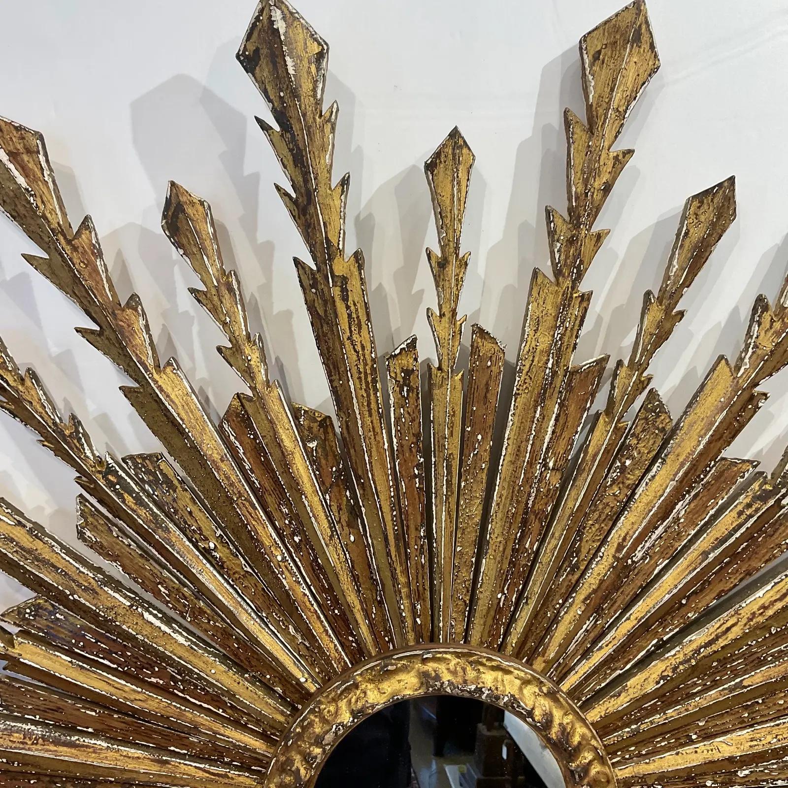 This is a beautiful early 20th century Italian  sunburst mirror! This is a stunning piece with wooden rays that are hand carved and gilded in gold with beautiful detail on the edges. This would make a wonderful show stopping addition to any home!