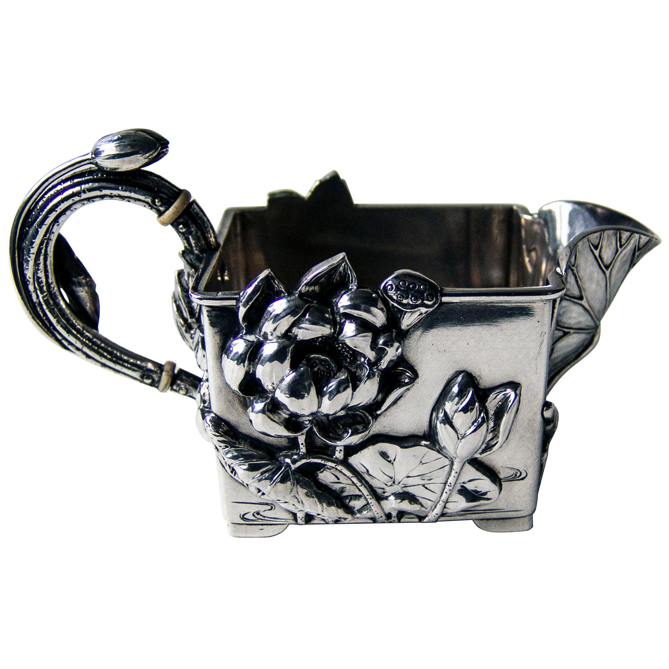 A superb Japanese heavy silver cream jug of rectangular form standing on four plain feet. All decoration in fantastic high-relief. The applied spout shaped as a Lotus leaf and the handle entwined with lotus bud and leaf. The four side panels