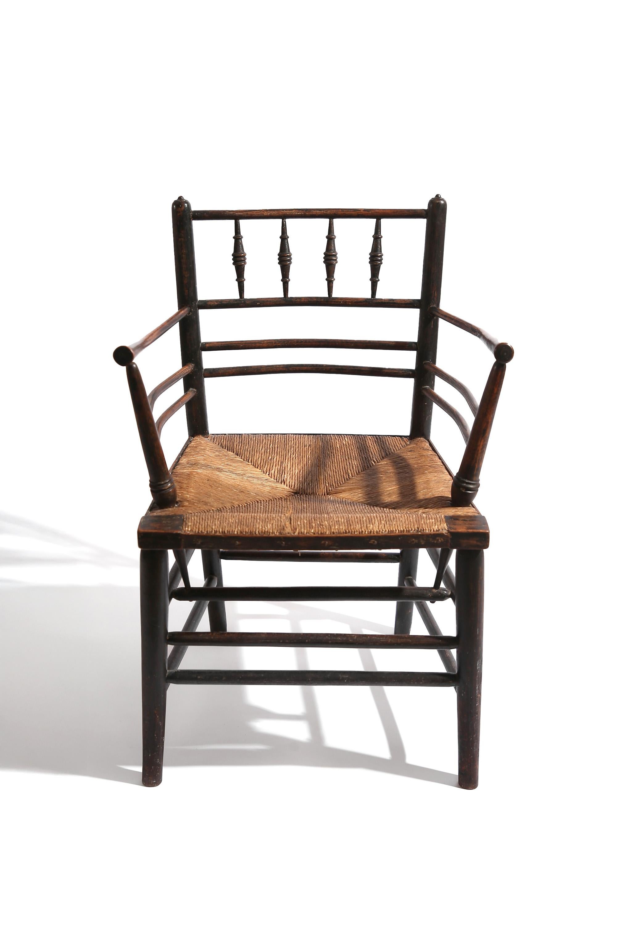 Rush-seated armchair in turned, ebonised wood frame and rush seat. In lovely original condition, the ebonised frame rubbed back to reveal the richly patinated wooden frame.

Retains the original rush seat, which has with some fraying commensurate