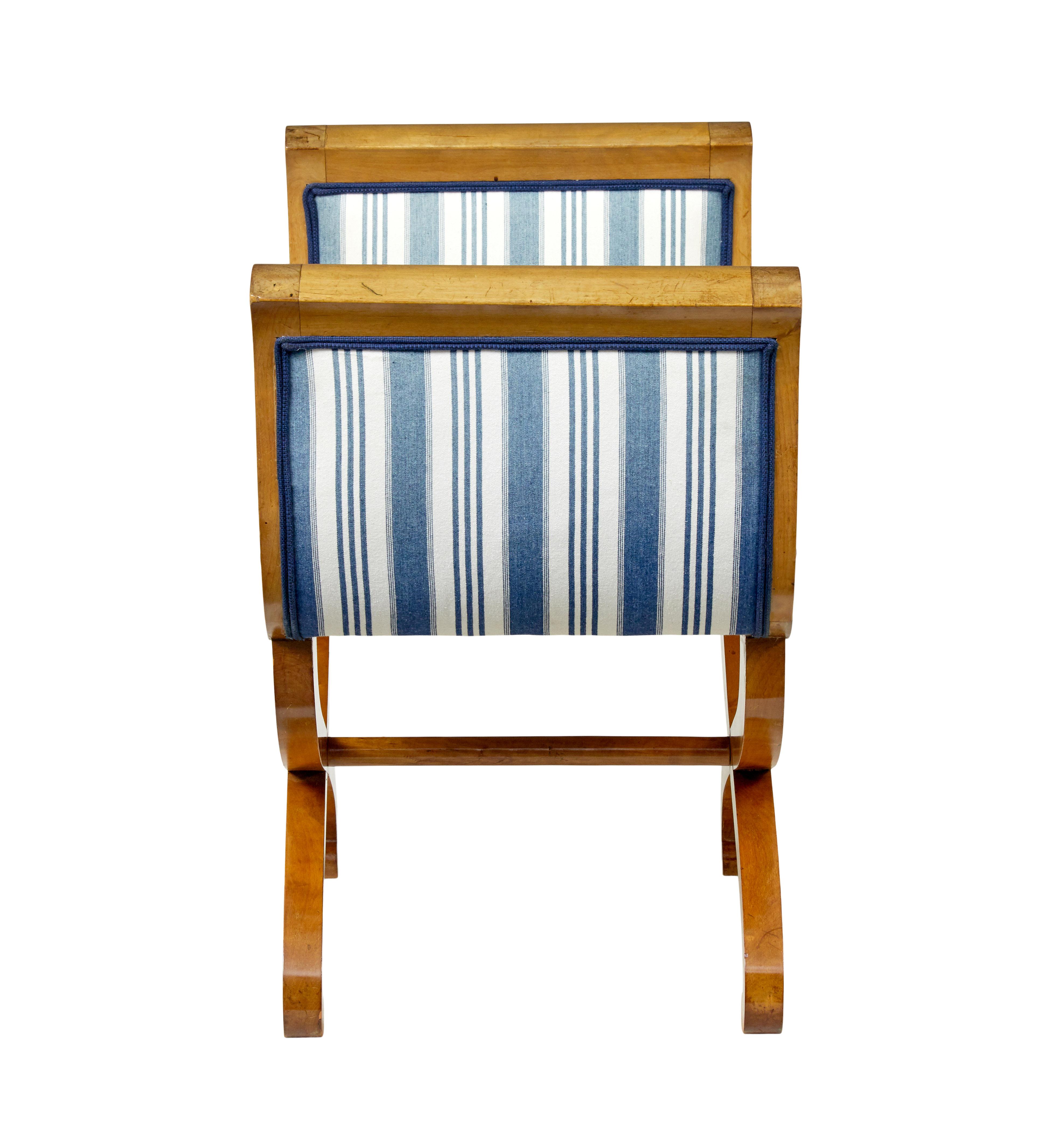 Tabouret curule suédois en bouleau du 19e siècle, vers 1890.

Elegant tabouret scandinave en bouleau aux influences empire. Bras en forme avec des éventails incrustés au sommet de chaque extrémité. Assise généreuse, garnie d'un tissu rayé bleu plus