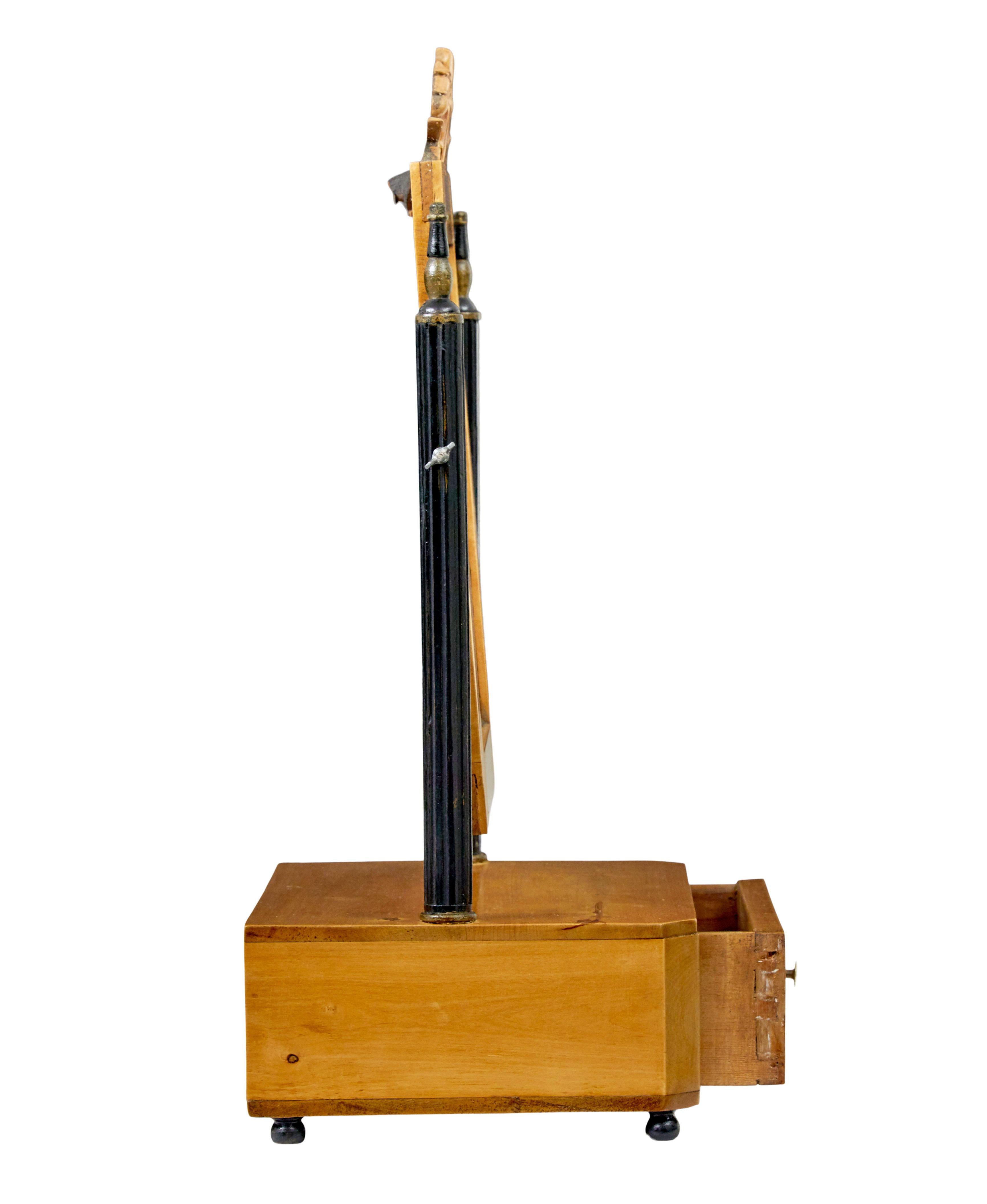 Spiegel aus schwedischer Birke, 19. Jahrhundert, um 1880.

Hochwertiger Tischspiegel aus Birke.

Rechteckiger Spiegel mit geschnitztem Gesims, schwenkbar zwischen einem Paar ebonisierter, kannelierter Stützen.  Rechteckiger Sockel mit einer einzigen