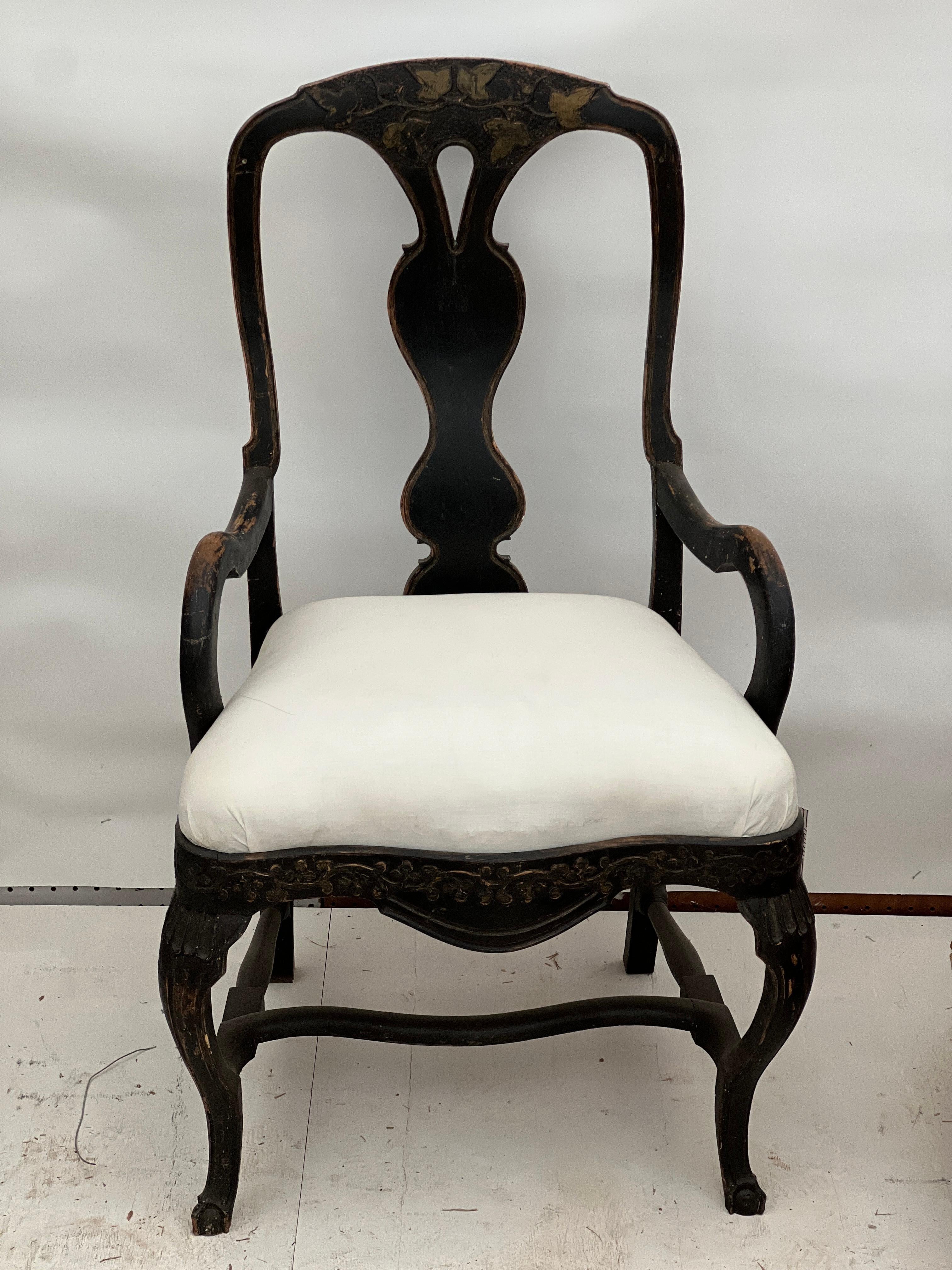 A stunning late 18th century/early 19th century Swedish Rococo armchair featuring black paint with natural worn patina coming through showcasing the original wood color with also deep green hues on the leaves. This is a stunning piece that could be