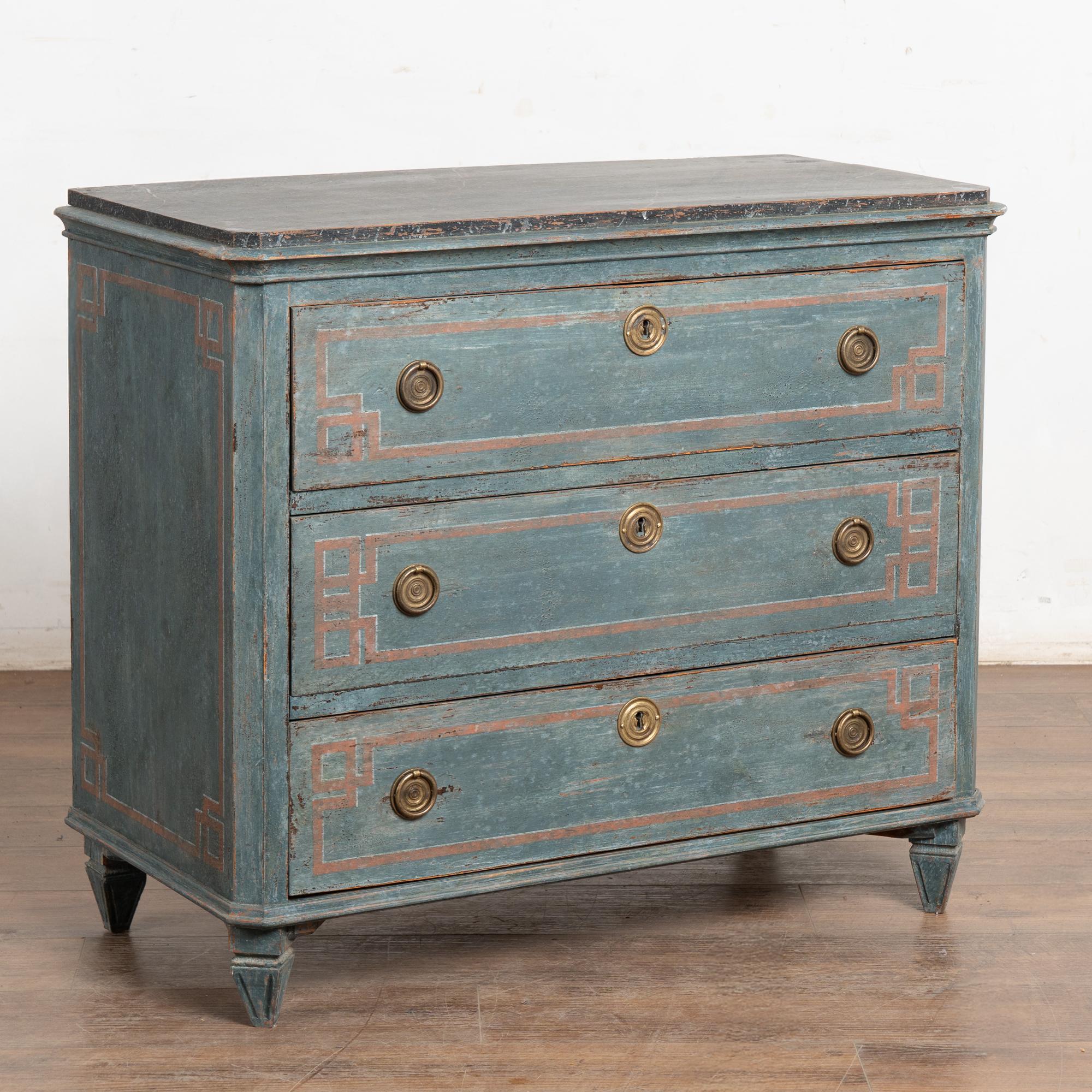 Una cassettiera decorativa in pino in stile gustaviano con tre cassetti e lati inclinati sollevati su quattro piedi scanalati e affusolati.
Restaurata, in seguito dipinta professionalmente con sfumature stratificate di blu tenue e accenti