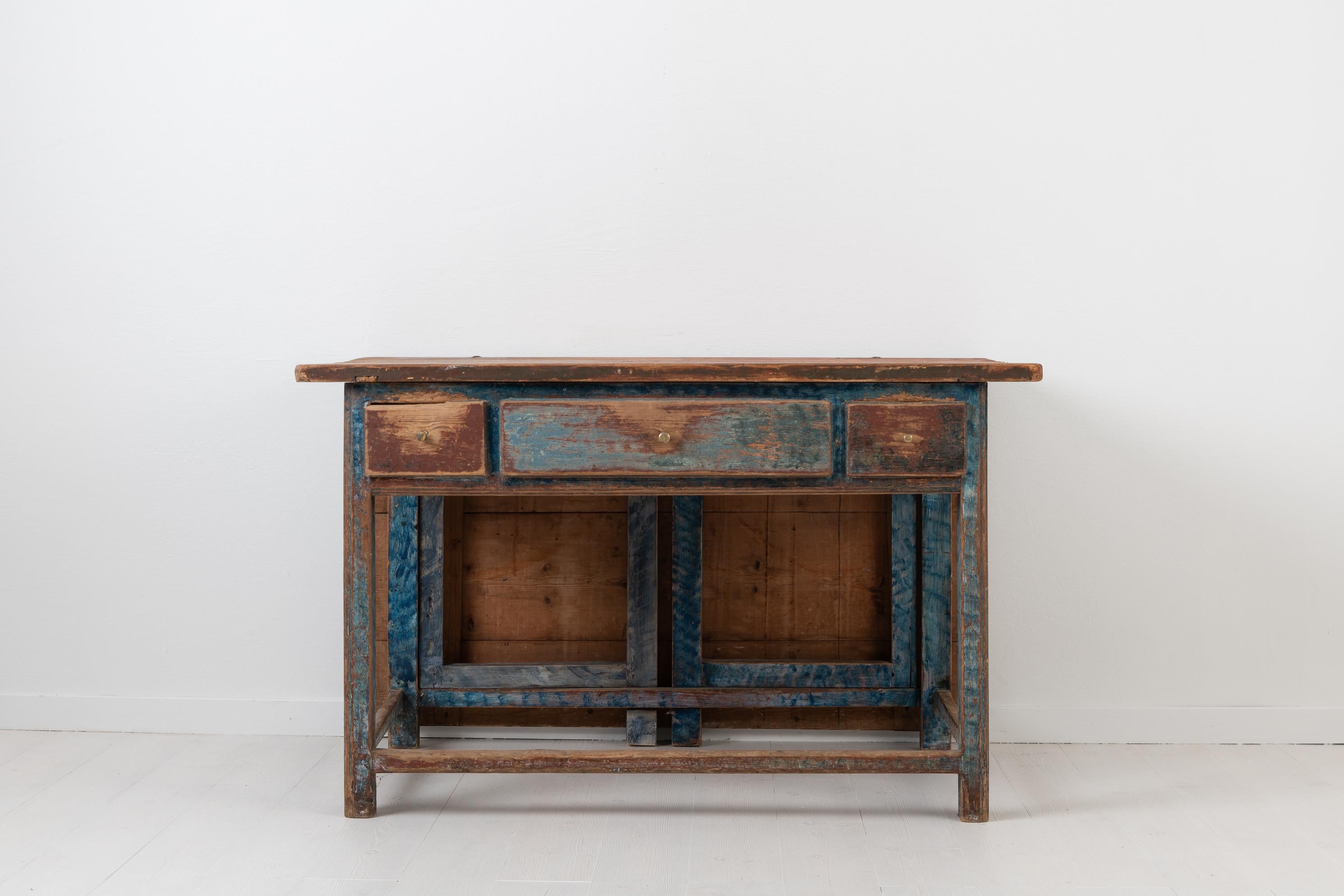 Mesa de trabajo azul de arte popular del norte de Suecia. La mesa se fabricó hacia 1810-1820 en pino sueco y está pintada con la pintura original. La pintura azul original está jaspeada en el marco, lo que es poco habitual. Pátina original