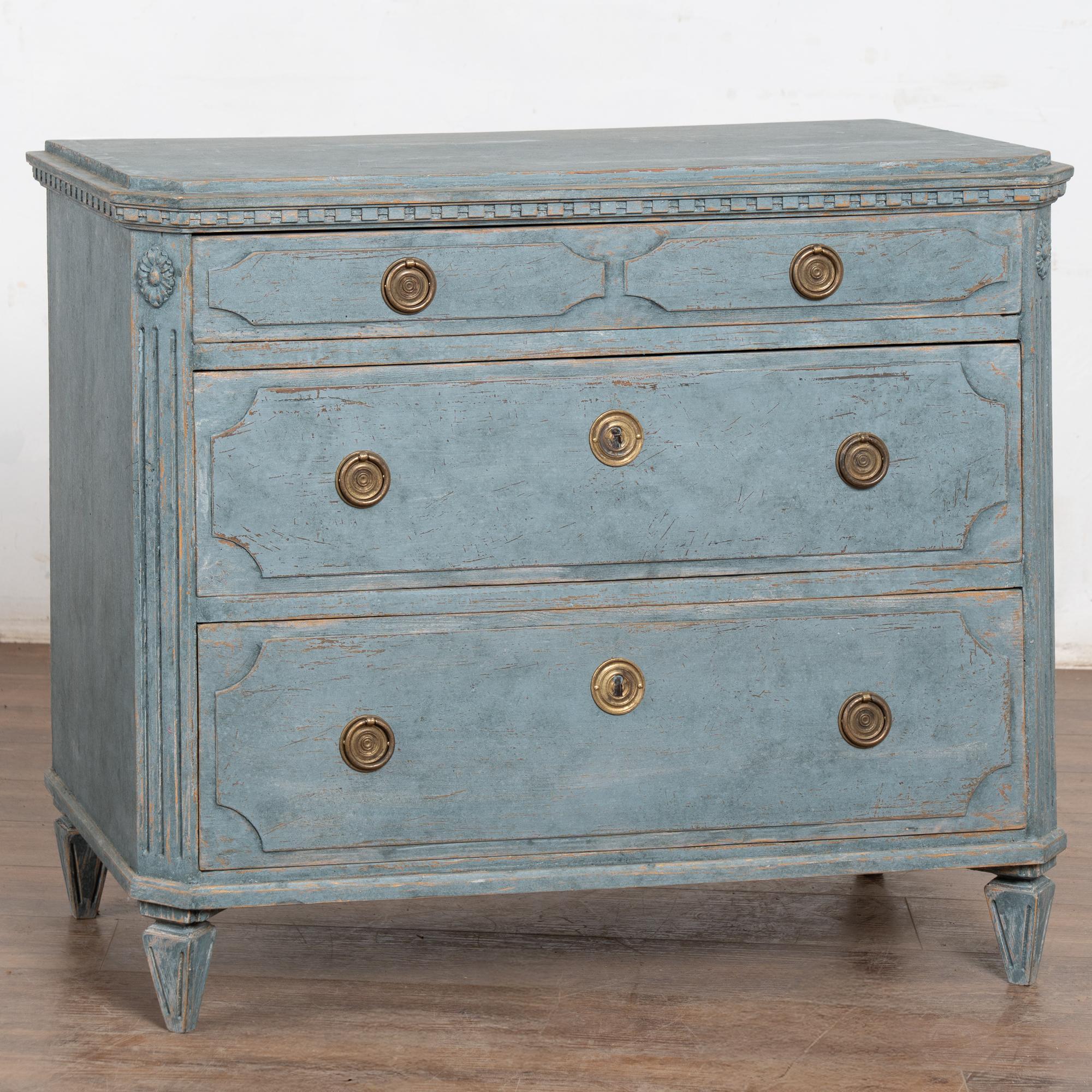 Questa bella cassettiera in pino gustaviano presenta pannelli in rilievo che decorano i tre cassetti.
La modanatura a dentello intagliata lungo la parte superiore, i dettagli laterali scanalati a sbalzo e i piedi scanalati delicatamente affusolati