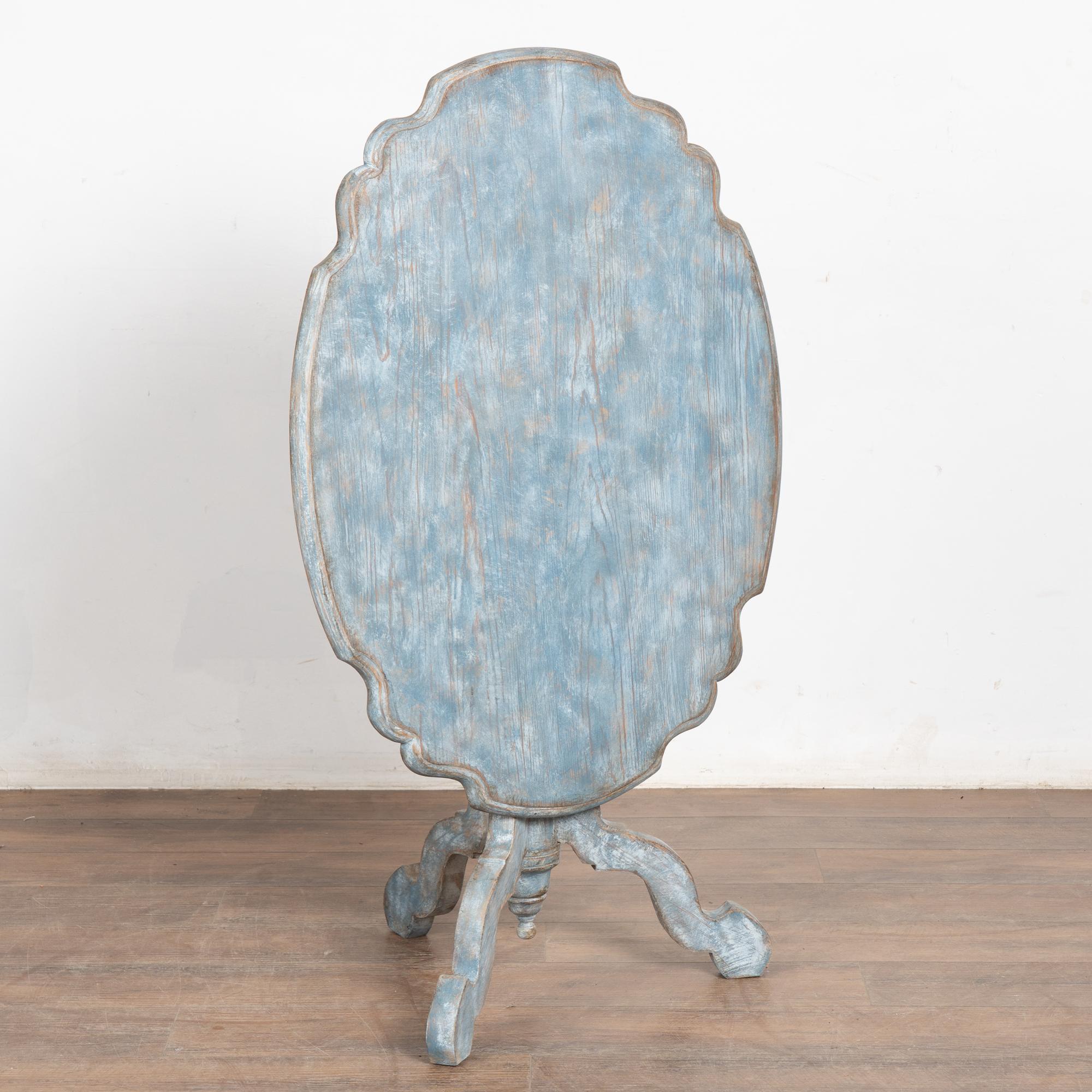 The attractive rococo curves draw one's eye to this delightful pine tilt-top tea table from Sweden.
Restored, newer professionally painted in layered shades of soft blue with white undertones and lightly distressed to fit the age and grace of this