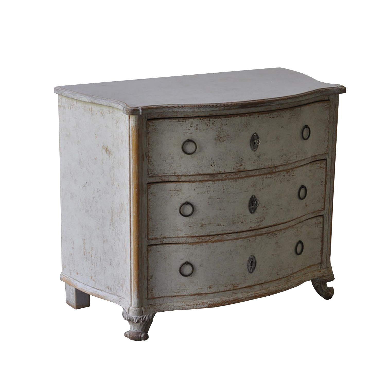 This 19th century bow front commode has three drawers with original hardware. It tapers to decorative carved feet.
