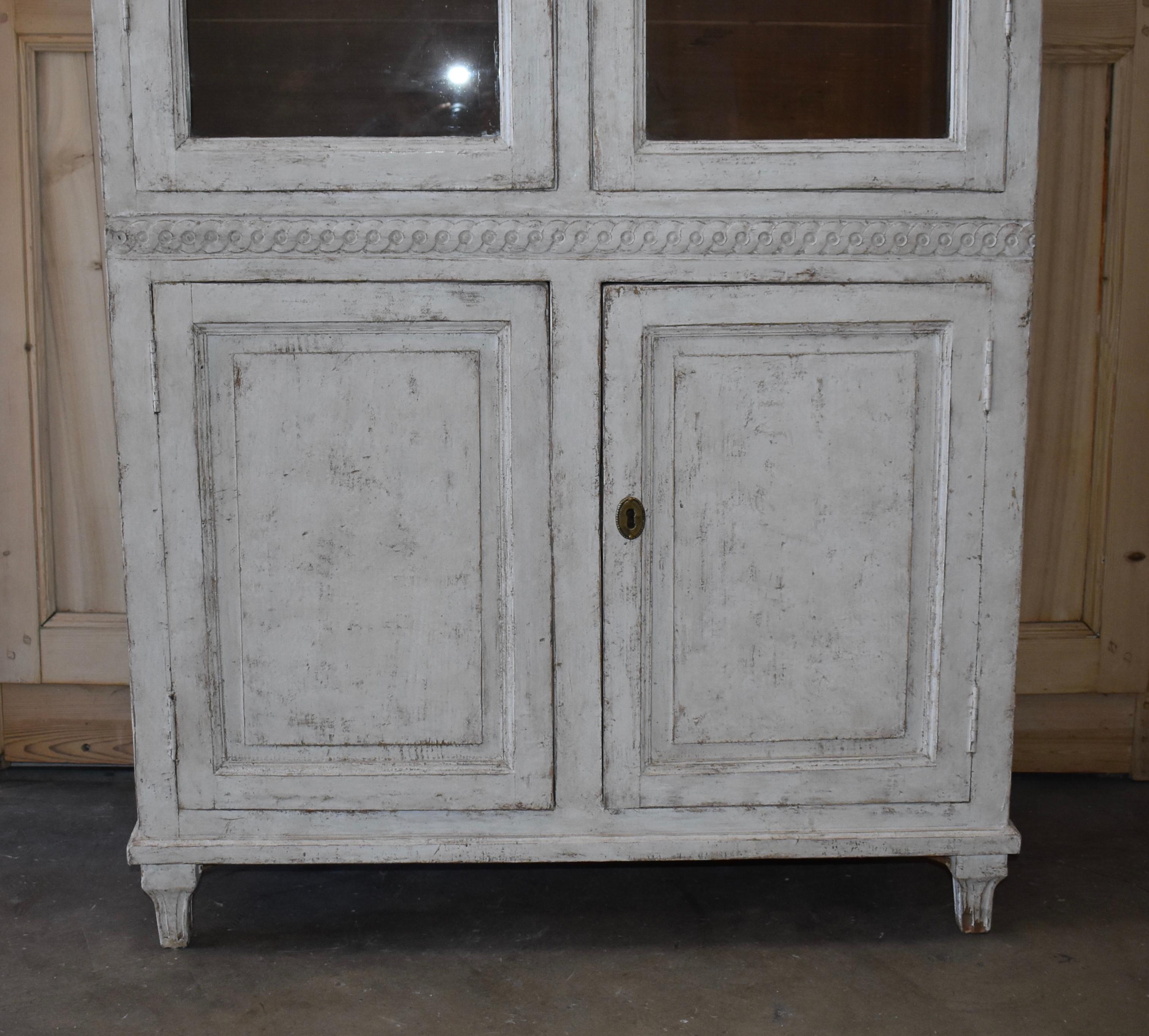19th century Swedish glass front library cupboard with original glass and carved detail. In the Interior are 2 shelves for storage. Lovely Swedish grey/white color.