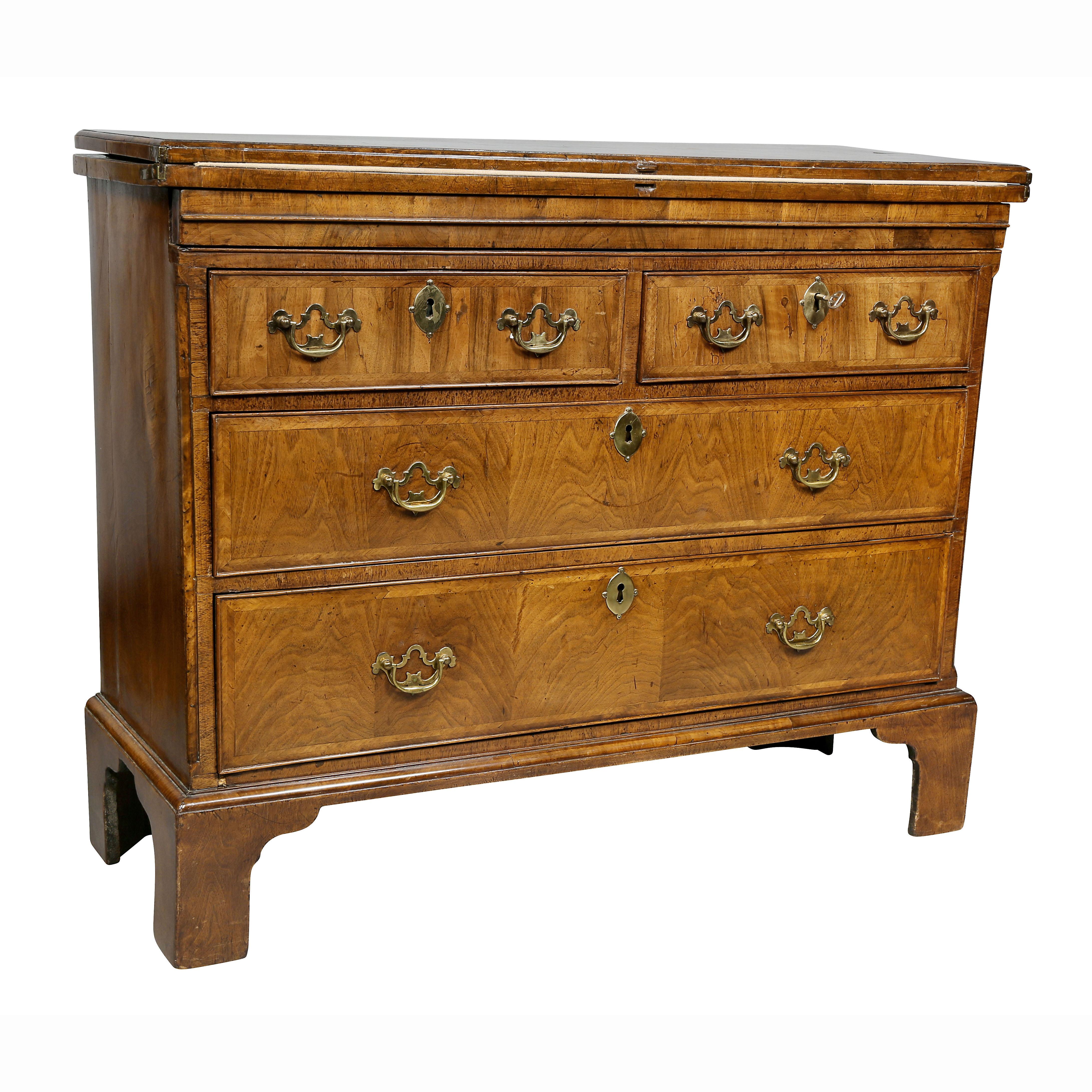 With rectangular hinged top with crossbanded edge, fabric lined interior over a hidden drawer that supports opened lid and two short drawers over two long drawers, raised on bracket feet.