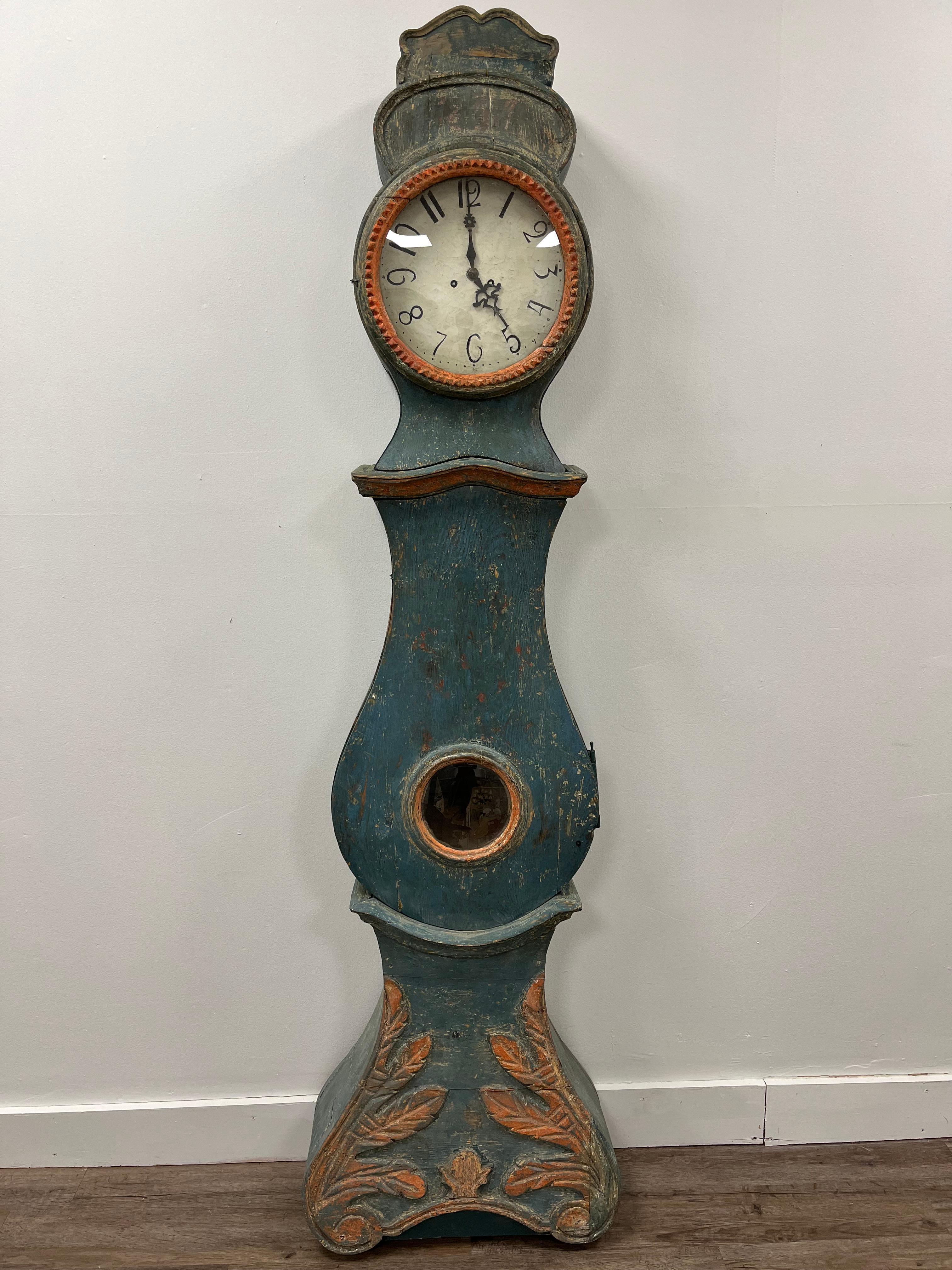 A unique Swedish case clock in original blue and salmon color. The year 1837 can faintly be seen above the clock face. Remnants of 18th century color animations are affixed to the interior. The base has unique leaf detailing. Clock is sold as a