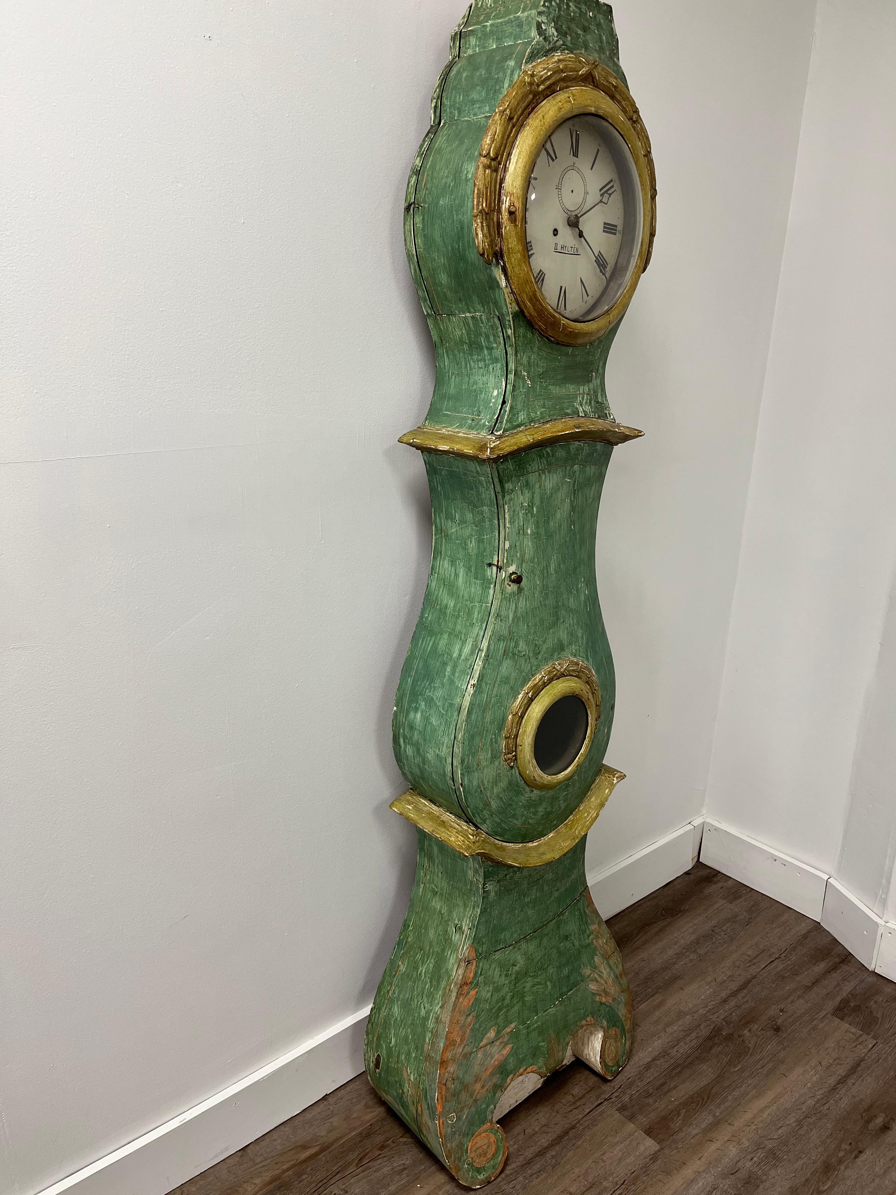 A tall Swedish case clock from Smaland with traditional wood carvings and unique plaster decor. Scraped to original green, gold, salmon and white paint. Clock is sold as a decorative piece, no mechanical guarantee. Weights, pendulum and key included.