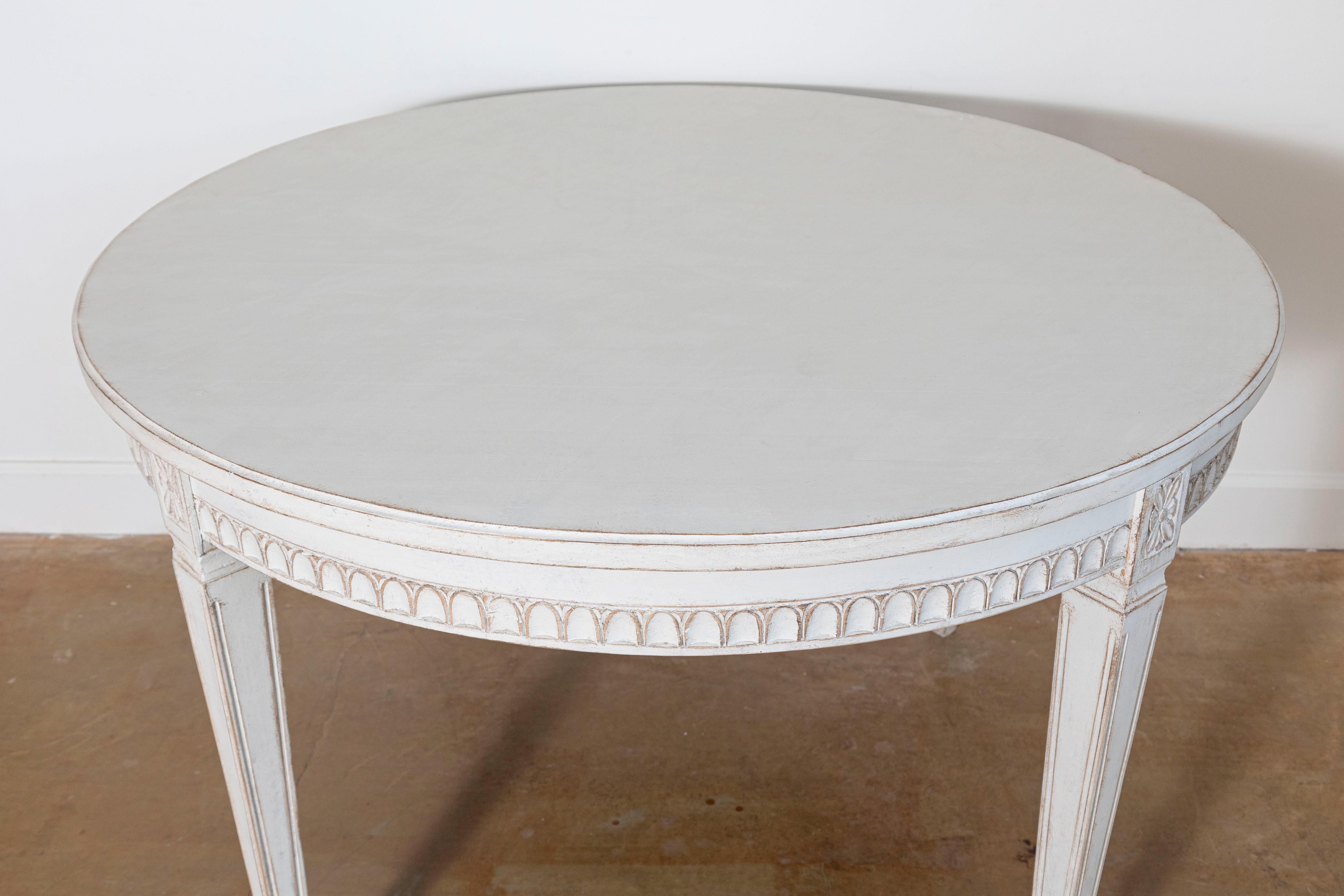 This elegant 19th-century Swedish center table is a beautiful example of Gustavian design, showcasing refined craftsmanship and timeless appeal. The table features a round top with clean lines, supported by four tapered and fluted legs adorned with