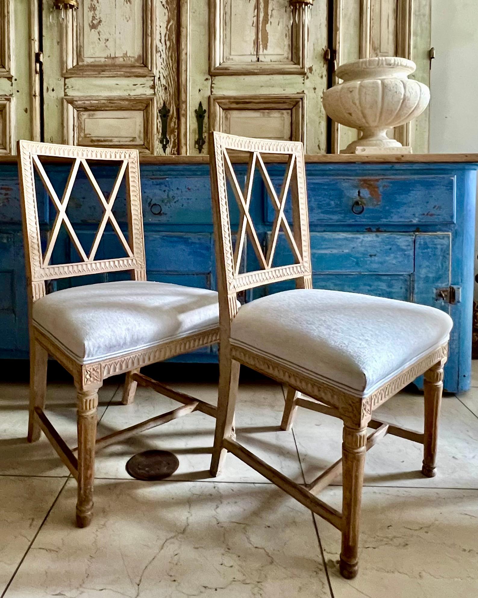 Pair of Swedish Gustavian Lindome chairs early 1800s with regtangular shaped back surranded by criss-cross pierced splats and frames carved in classic Gustavian motifs.
Hand scraped to its most original color with some remants showing.
Upholstered