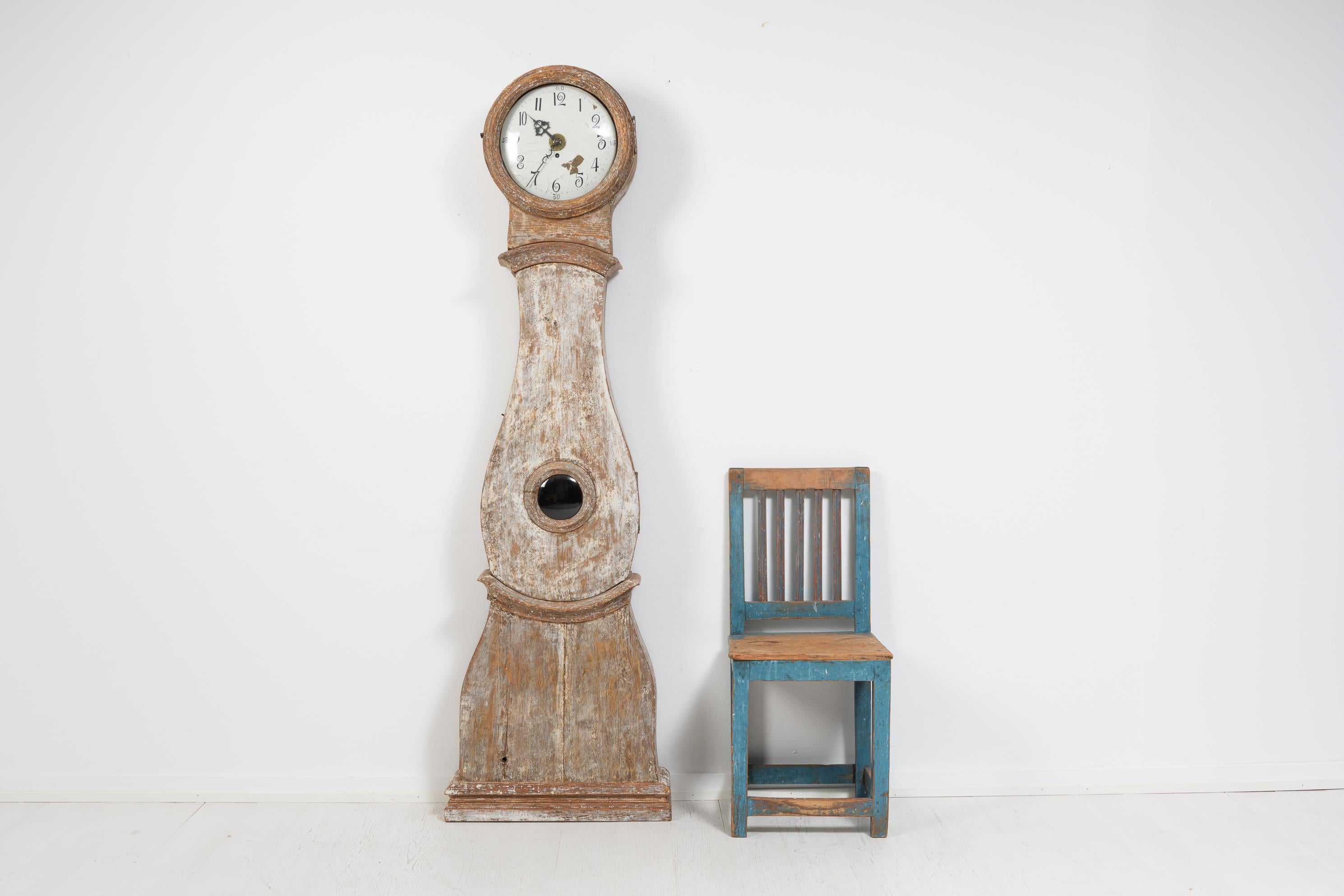 Pendule classique à long boîtier de style rococo de Suède, fabriquée entre le début et le milieu du 19e siècle, de 1820 à 1840. L'horloge est en pin peint et a été grattée à sec à la main jusqu'à la couche de peinture actuelle.

L'horloge est