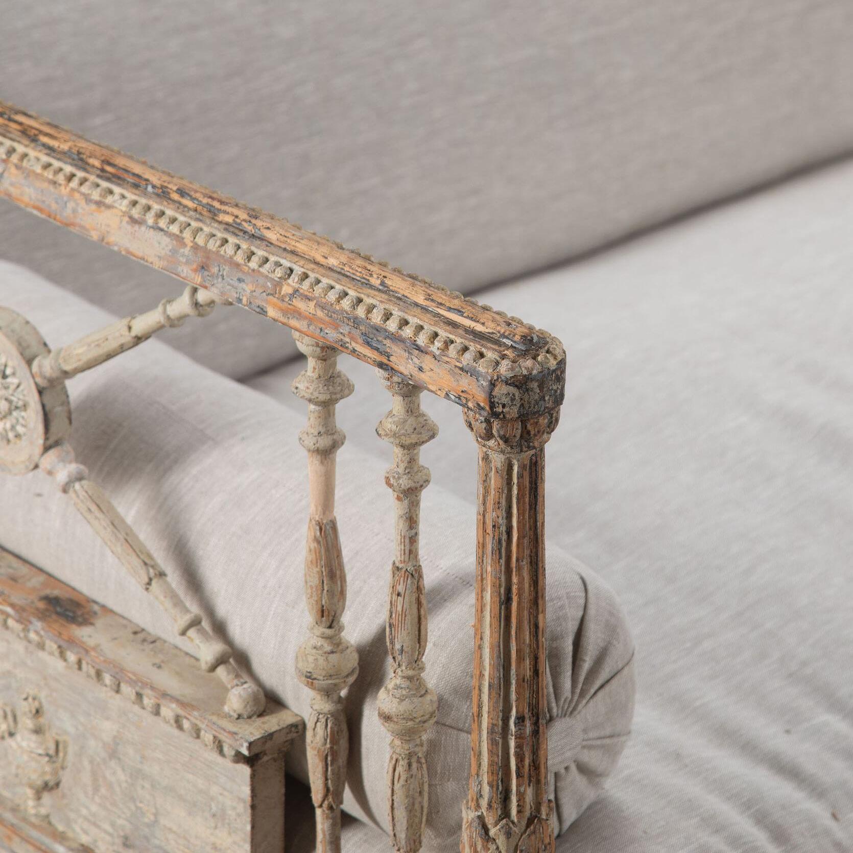 Un insolito divano gustaviano d'epoca con decorazione classica in gesso. 
Con rari piedi a zampa di leone e vernice originale scrostata. Rivestito di recente in lino.