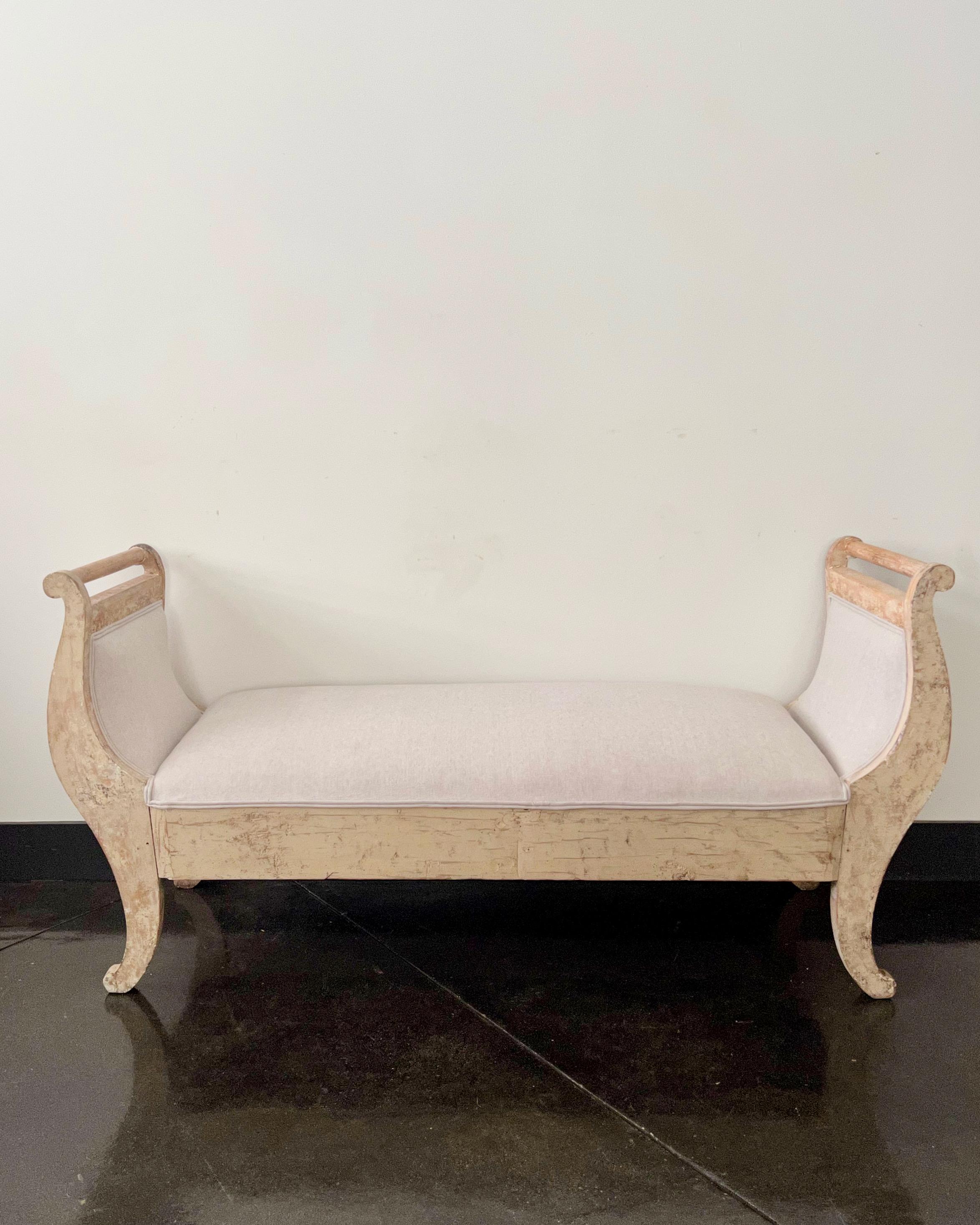 A charming small daybed / settee scraped to its most original finish and newly upholstered in linen. This bench has a timeless appeal for any setting.