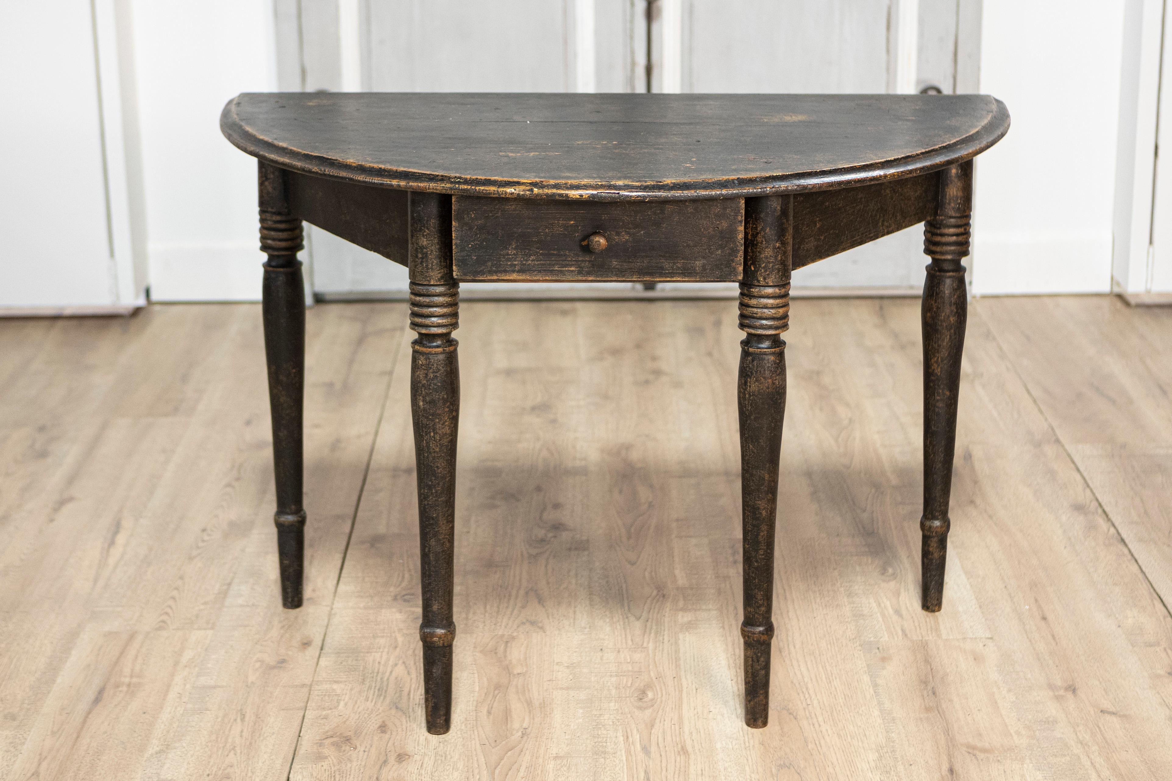 Cette console suédoise en demi-lune du XIXe siècle, vers 1860, est un bel exemple du design scandinave classique. Fabriqué en pin massif, il présente un plateau en forme de demi-lune qui repose gracieusement sur quatre pieds tournés, faisant preuve