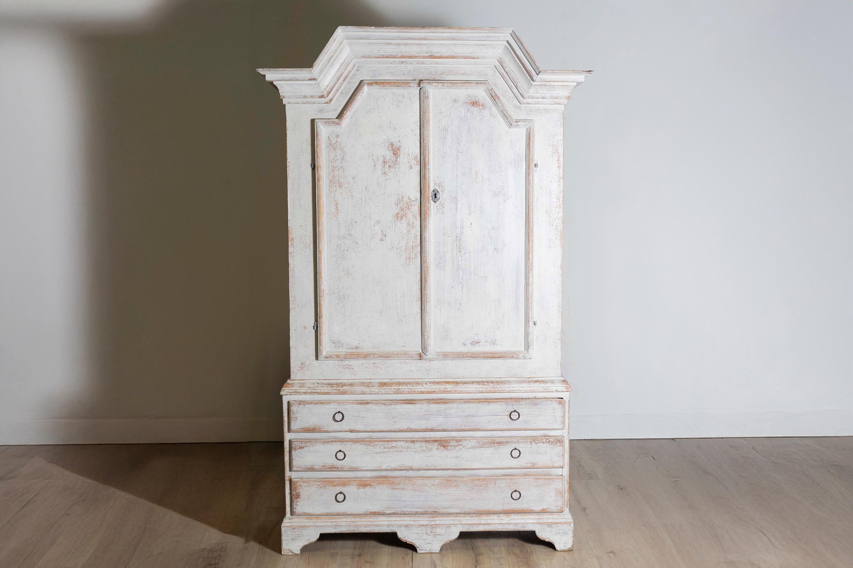 This 19th-century Swedish Folk Art cabinet, circa 1810, is an exquisite example of rustic craftsmanship blended with functional design. Made from solid wood, it features a beautifully distressed painted finish in a soft, muted hue typical of Swedish