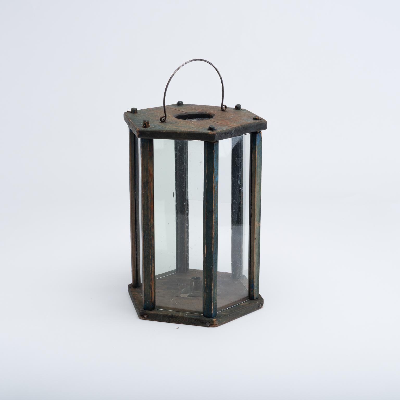 Folk Art lantern manufactured from Swedish pine. The blue paint is original. The lantern has wooden decorations on the top as well as six glass panels covering the sides. There is a candleholder in brass at the bottom of the lantern with room for