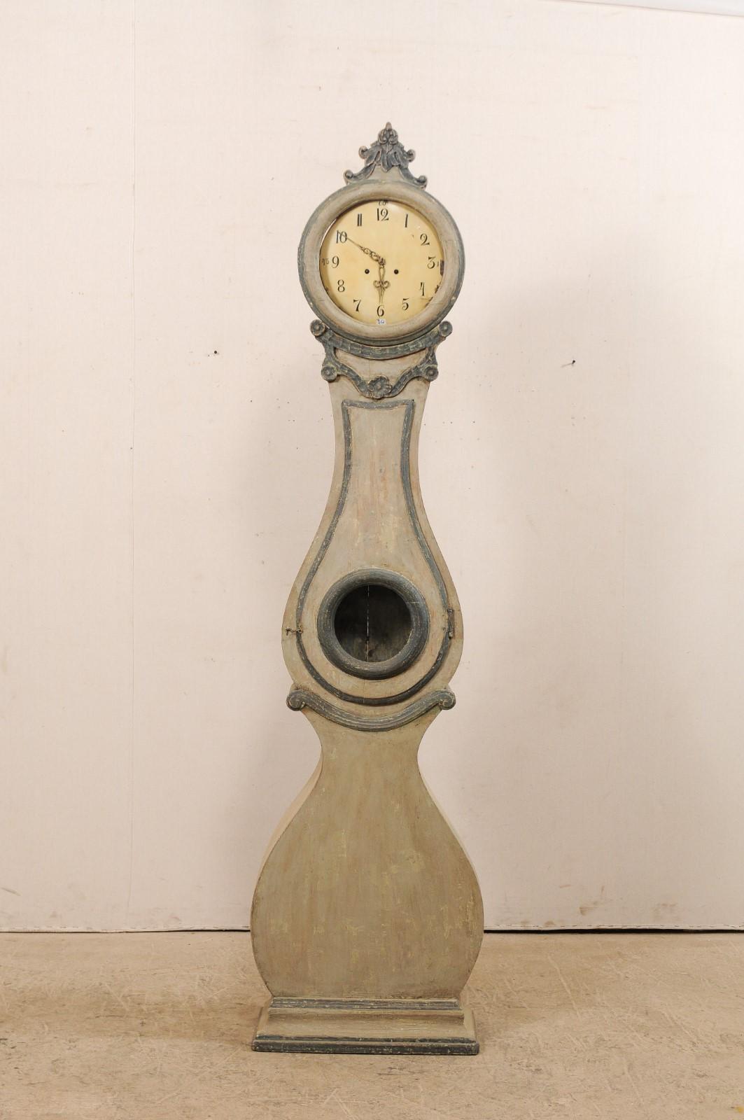 Horloge suédoise Fryksdahl du 19ème siècle avec un corps galbé et une couronne sculptée. Cette horloge antique Fryksdahl de Suède possède de fabuleuses garnitures qui mettent en valeur et accentuent cette horloge aux formes harmonieuses. L'horloge