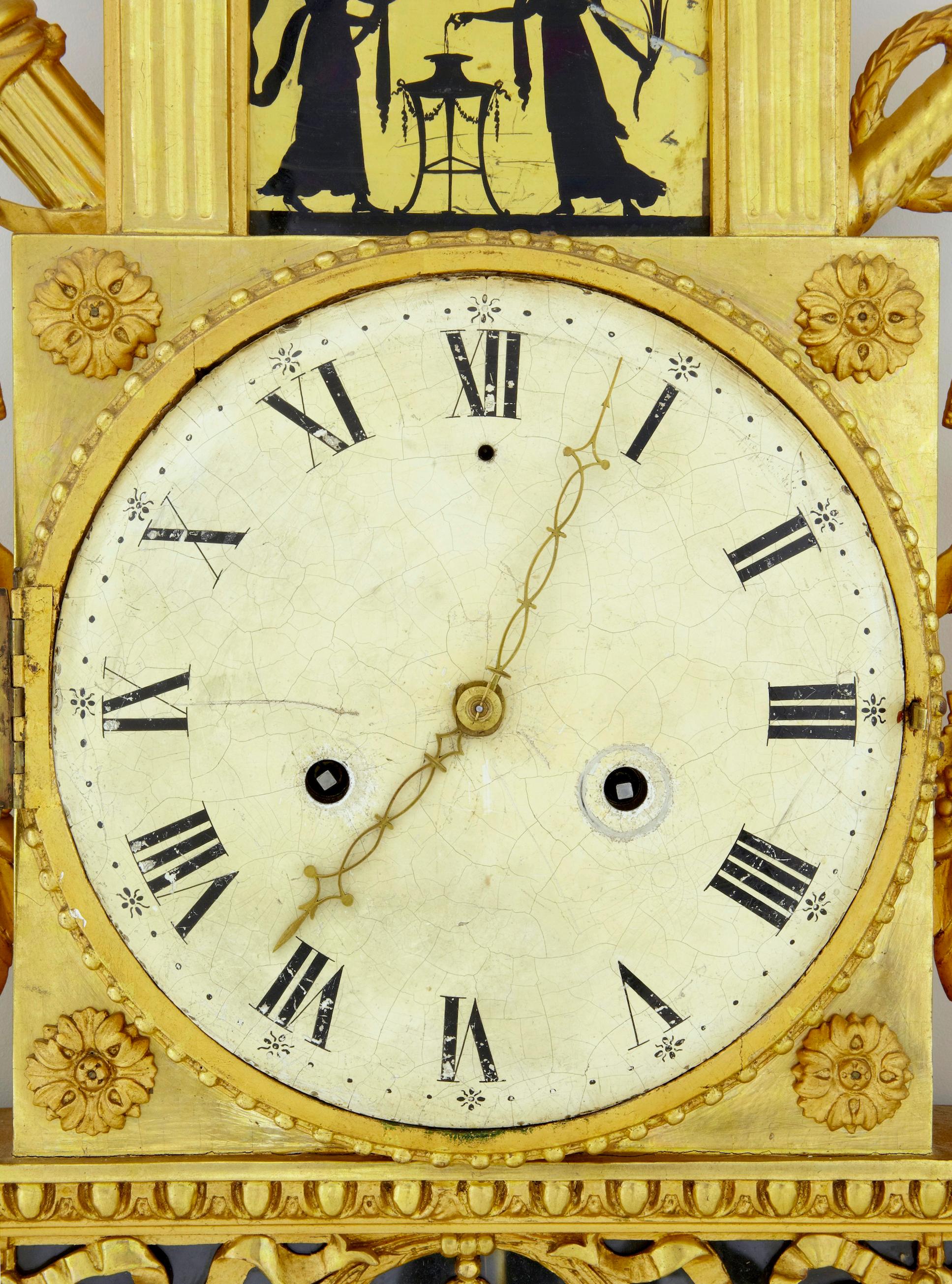 19th century Swedish gilt and églomisé ornate wall clock circa 1840.

Fine quality Swedish wall clock of the empire period circa 1840. Beautifully carved, surmounted with doves. 2 silhouette églomisé glass panels (1 of which has a break).