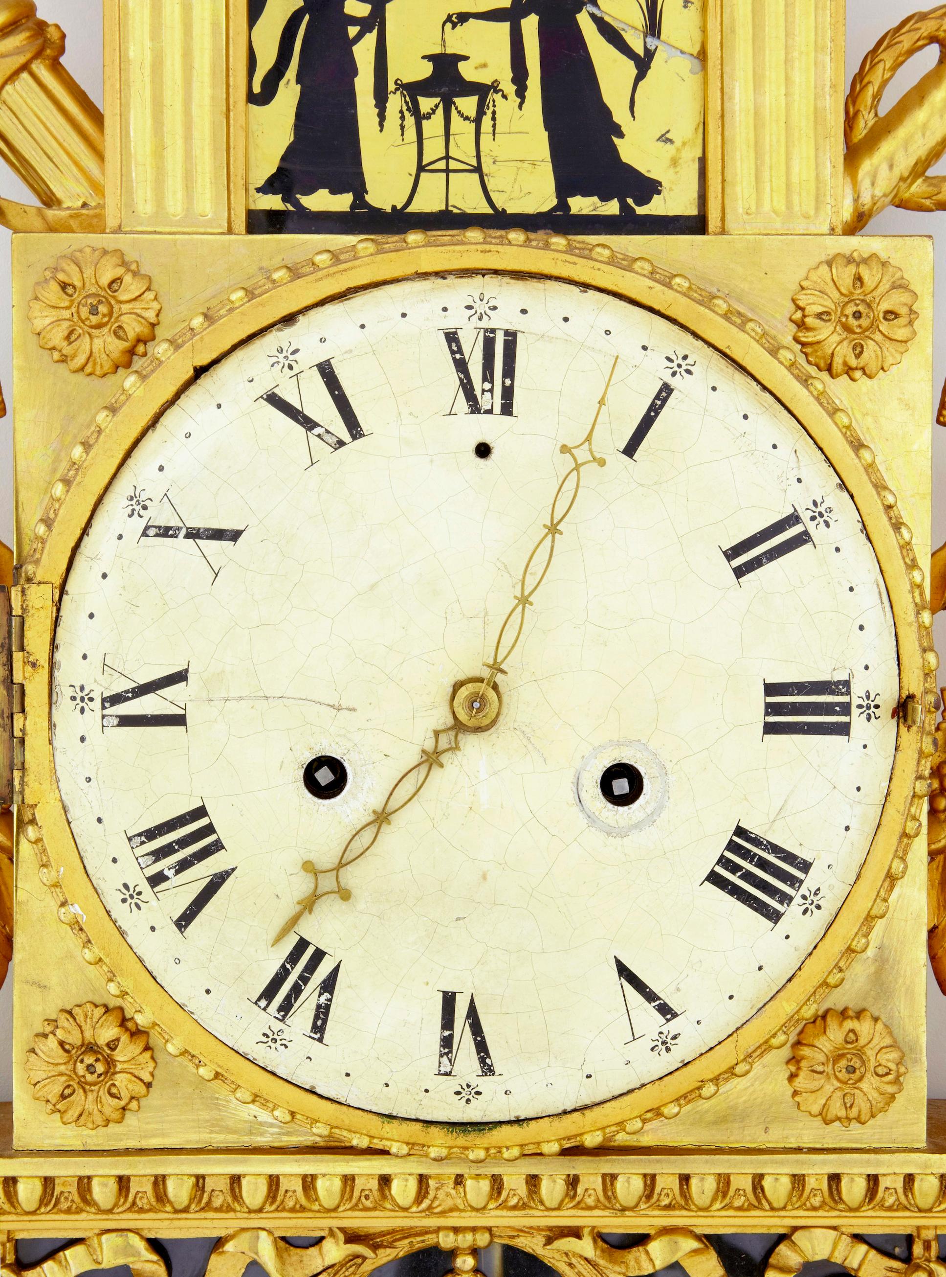 19th century Swedish gilt and églomisé ornate wall clock circa 1840.

Fine quality swedish wall clock of the empire period circa 1840. Beautifully carved, surmounted with doves. 2 silhouette églomisé glass panels (1 of which has a break). Craquelure