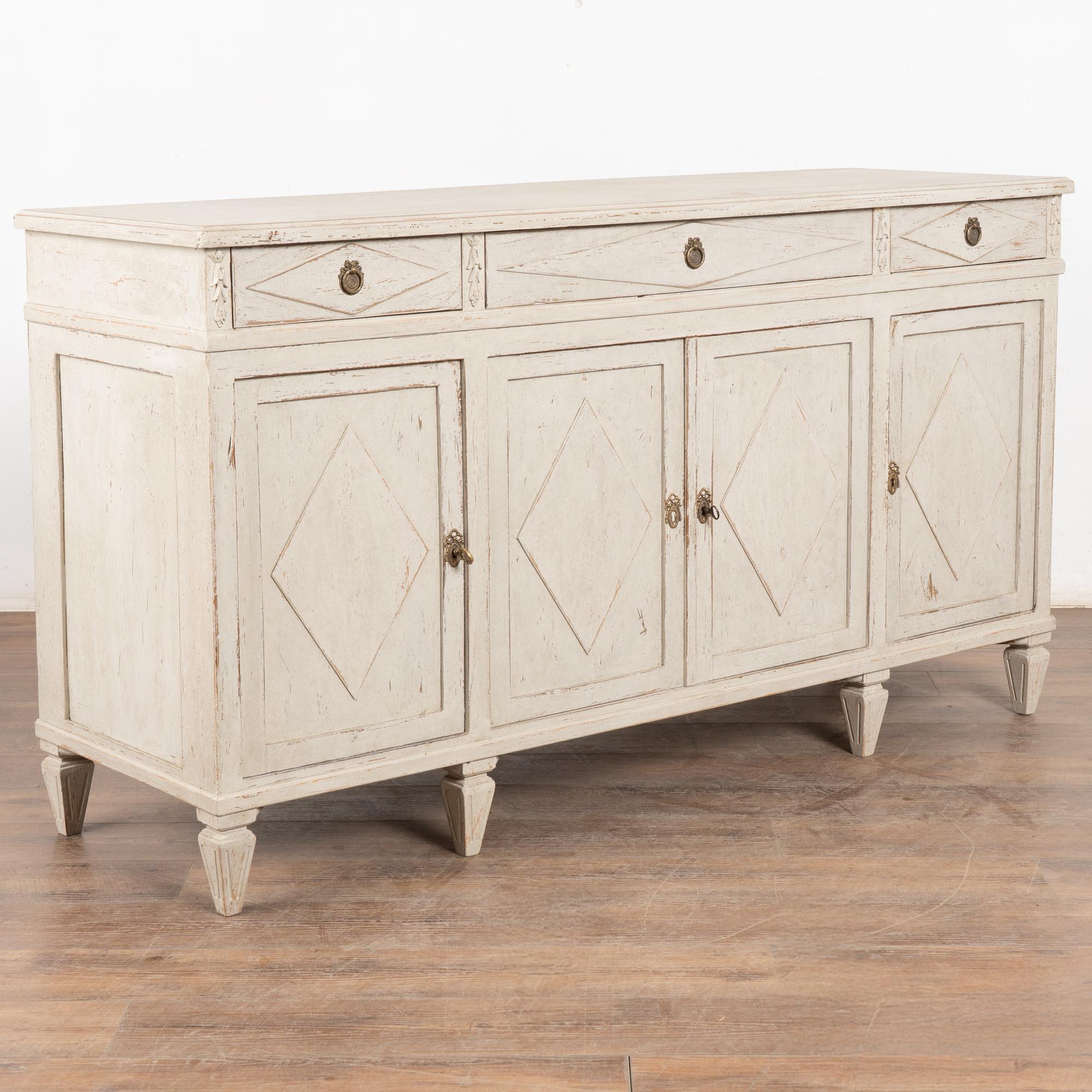 Swedish sideboard buffet with traditional diamond motif in drawers and door panels. 
Three drawers over four cabinet doors, one long interior shelf.
Restored, later professionally painted in layered shades of gray and lightly distressed to fit the